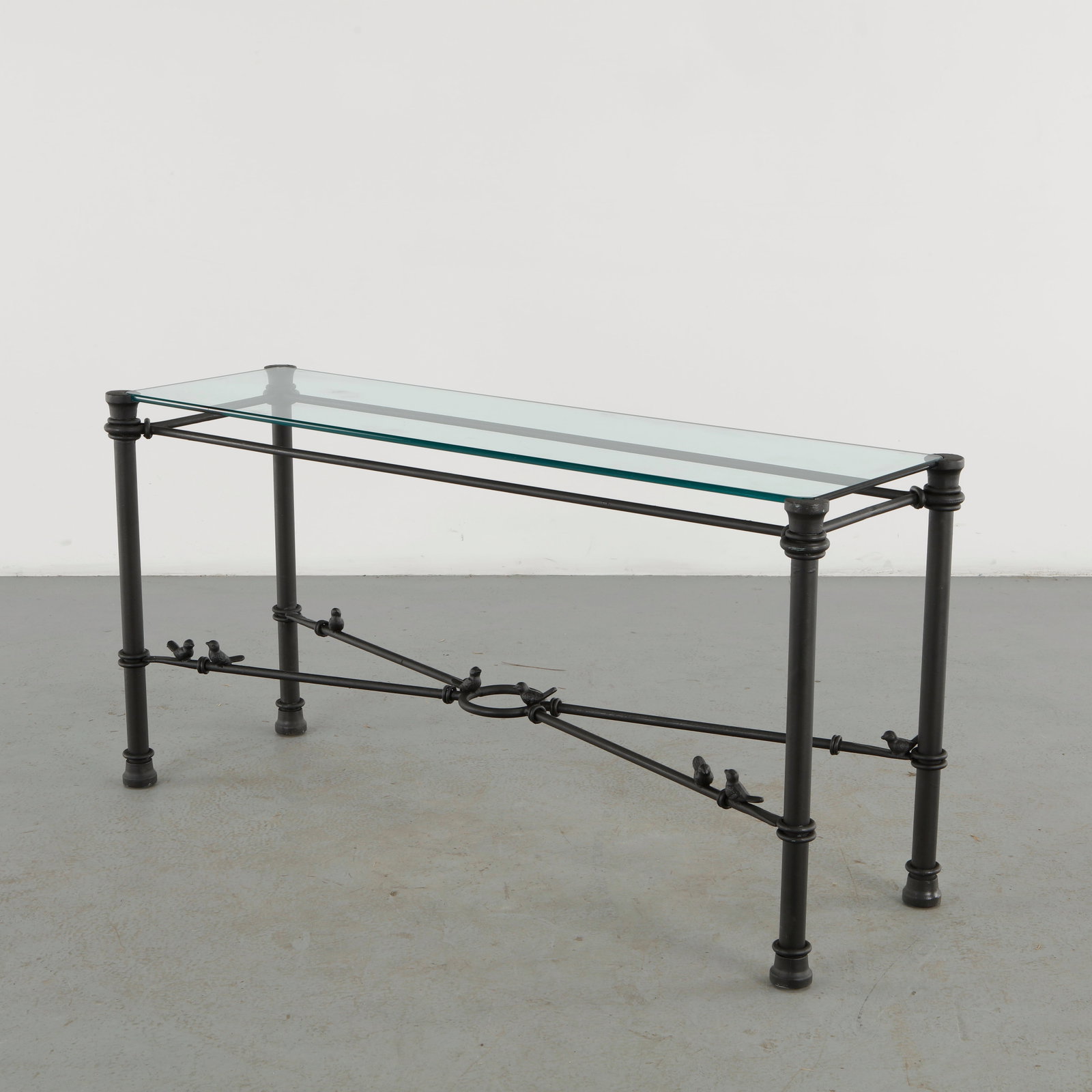 Glasse Console in the style of Diego Giacometti: A striking glass console in the style of Diego Giacometti, featuring a dark forged-metal structure enriched with small naturalistic bird details. The slender architectural framework contrasts beautifu