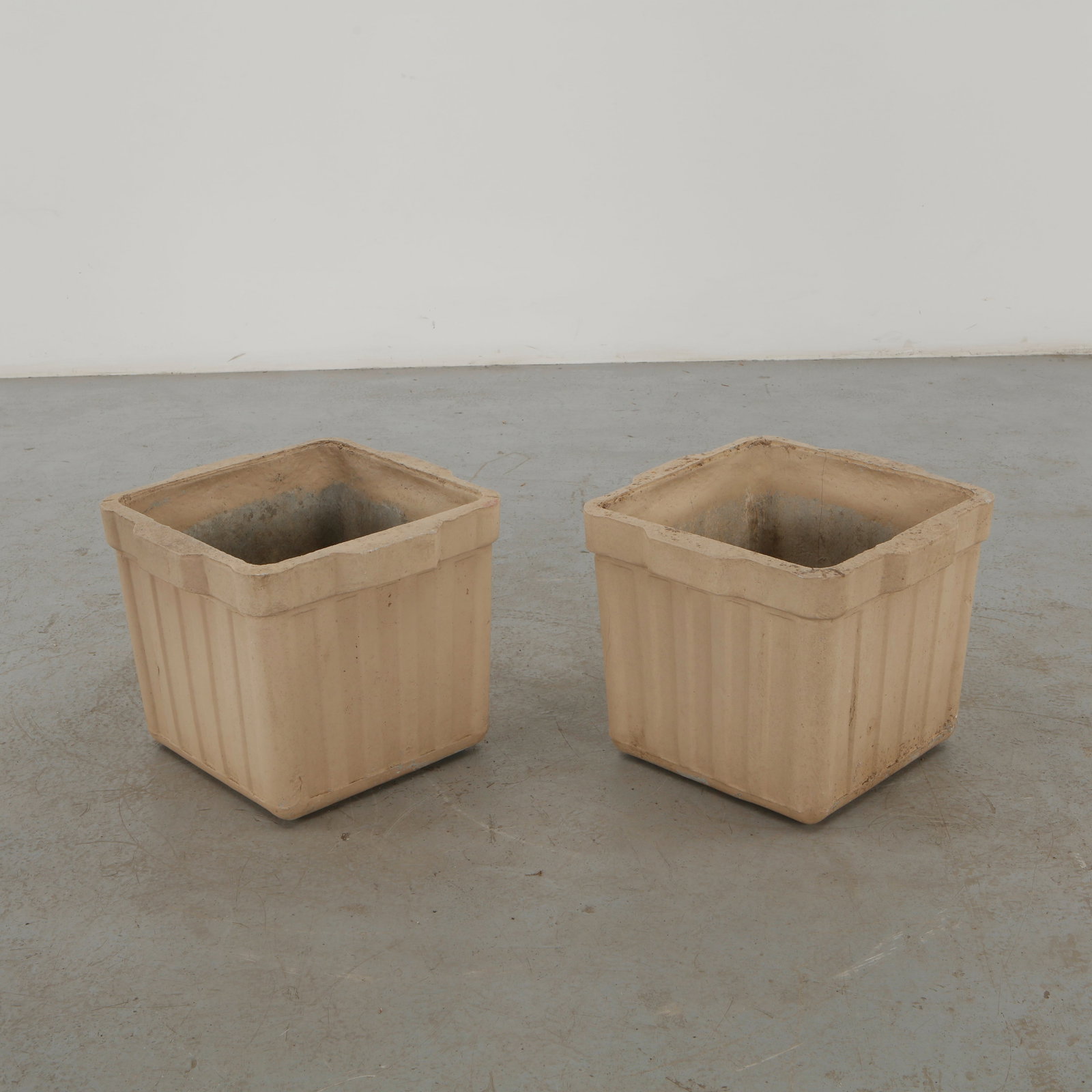 Willy Guhl, Pair of Square Fluted Planters, 1960s: Willy Guhl pair of square concrete planters distinguished by vertically fluted walls and substantial raised rims. Their restrained geometry and weathered white finish exemplify Guhl enduring approach