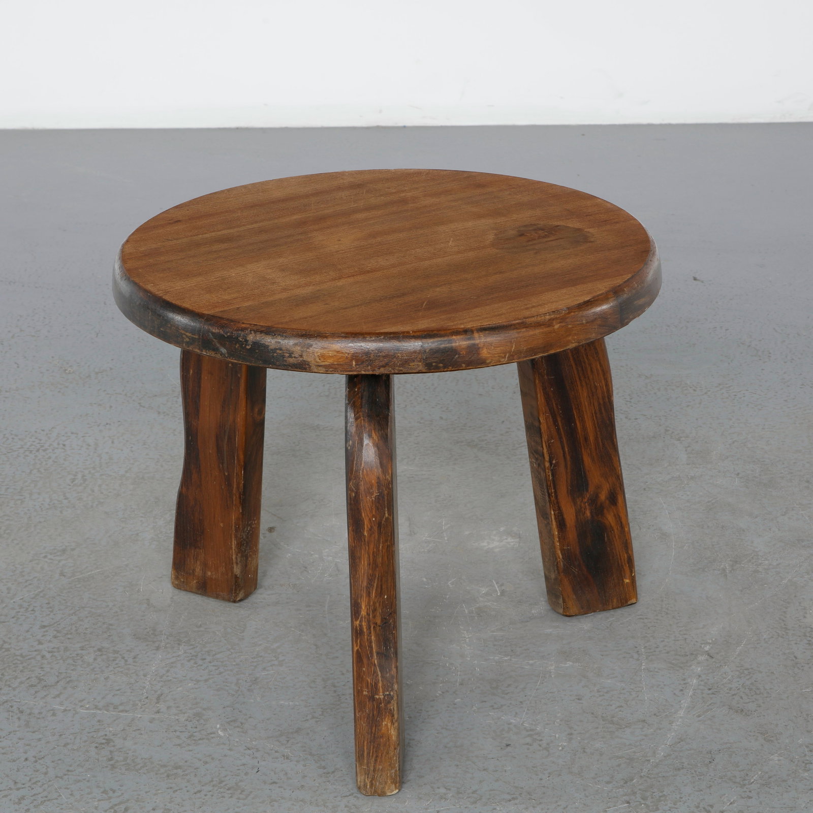 Rustic Three-Legged Side Table, France, 1960s: A handcrafted three-leg side table in solid wood, featuring sculptural organic legs and a thick circular top with a rich natural grain. Its primitive aesthetic and robust construction reflect the endu