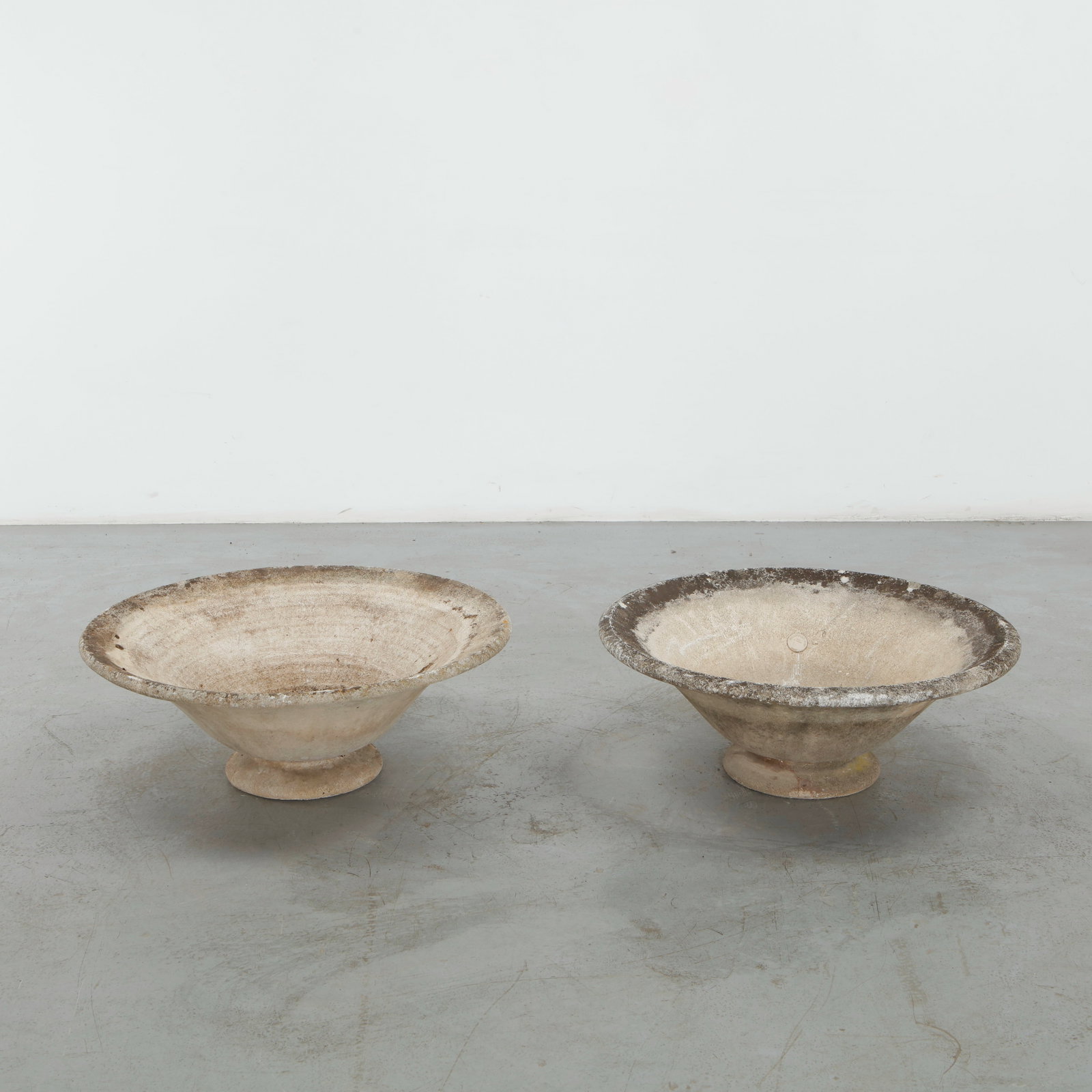 Grandon Fres, Pair of Pedestal Concrete Planters, 1960s: A distinctive pair of round concrete planters raised on gently stepped pedestal bases, combining broad, shallow basins with restrained sculptural profiles. The naturally weathered surfaces and rich