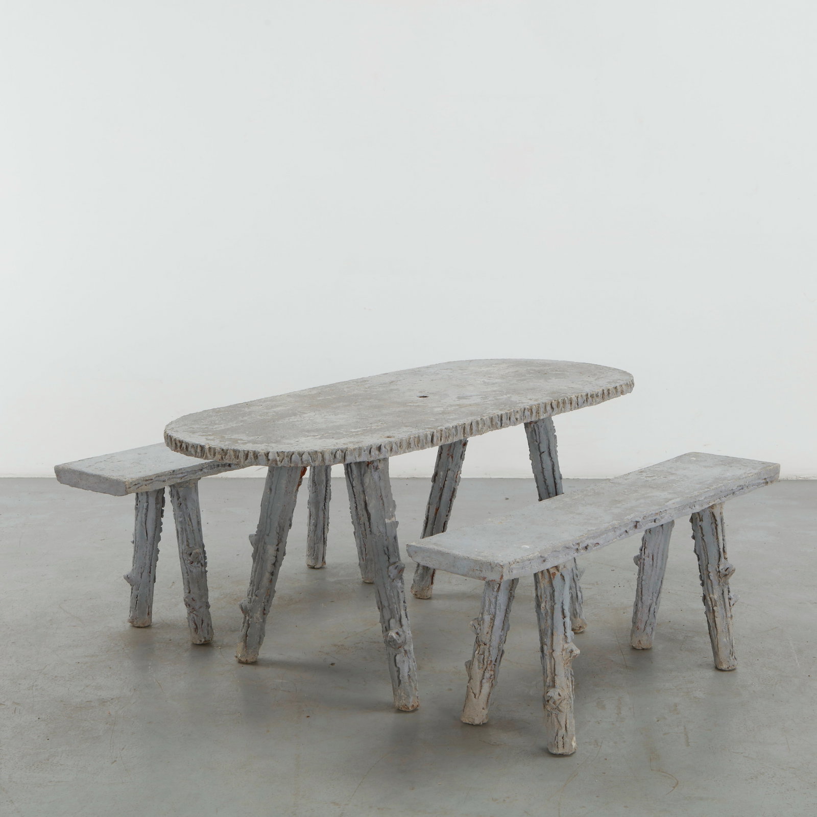 Faux Bois Outdoor Dining Set, 1960s: A sculptural faux bois outdoor dining ensemble comprising a substantial oval table and two matching benches, convincingly executed in molded concrete to imitate the texture of rough-hewn timber. The i