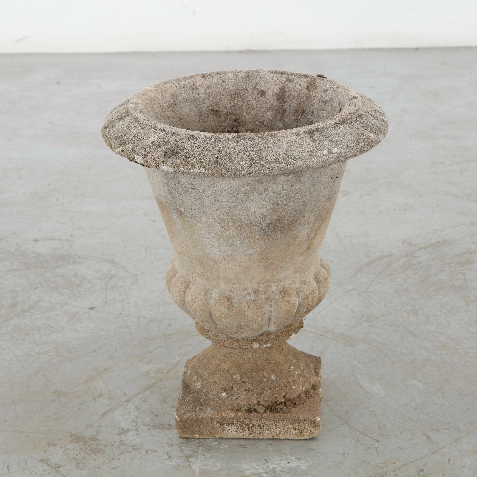 Cast Stone Urn Planter, 1960s: Cast stone urn planter distinguished by its lobed body, substantial rim, and square architectural base. The aged finish and softened contours lend the piece a commanding garden presence. Height: 17