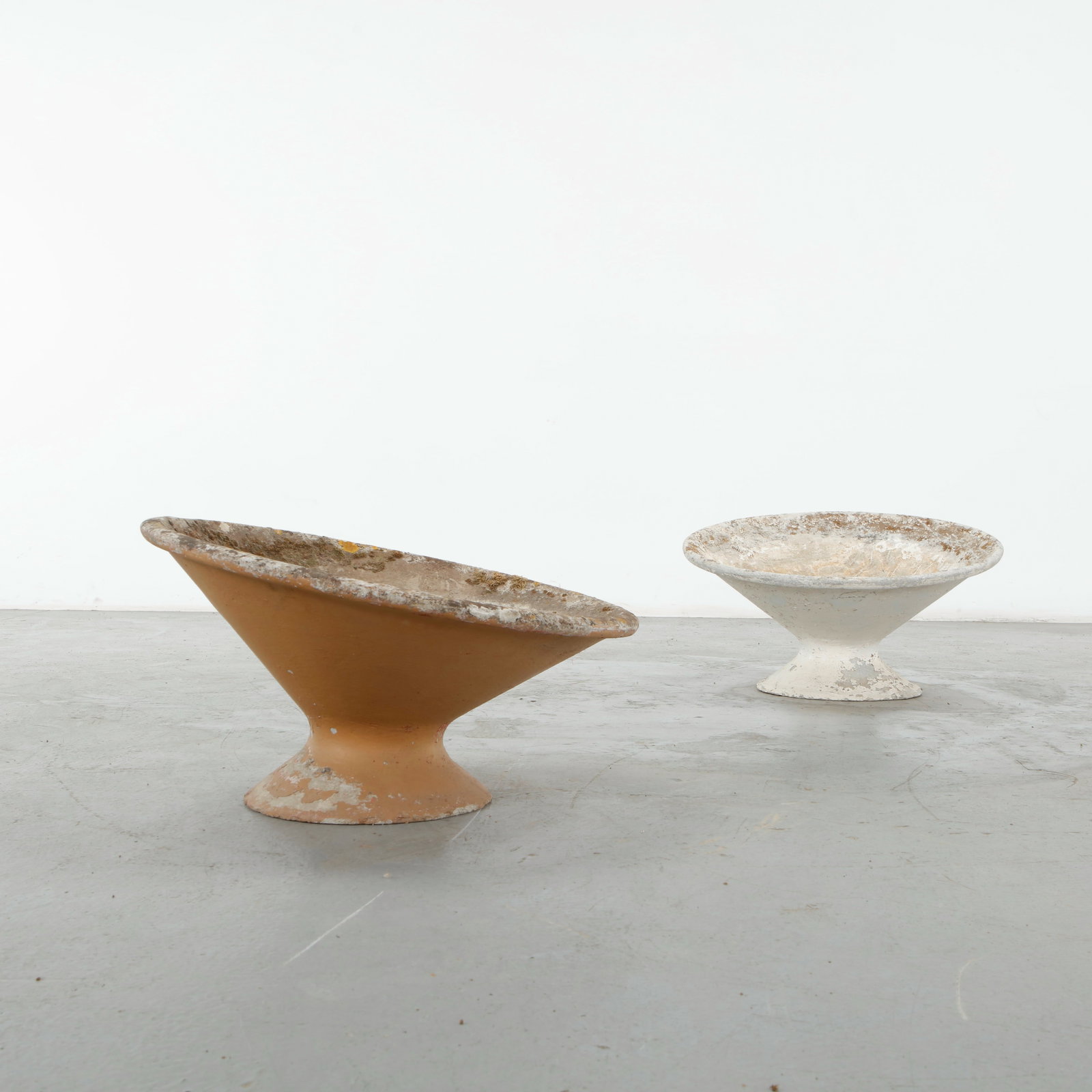 Willy Guhl, Pair of Off-Kilter Planters, 1960s: A rare pair of sculptural concrete planters characterized by dramatically irregular, undulating profiles and generously flared openings. Their asymmetrical silhouettes and richly weathered surfaces