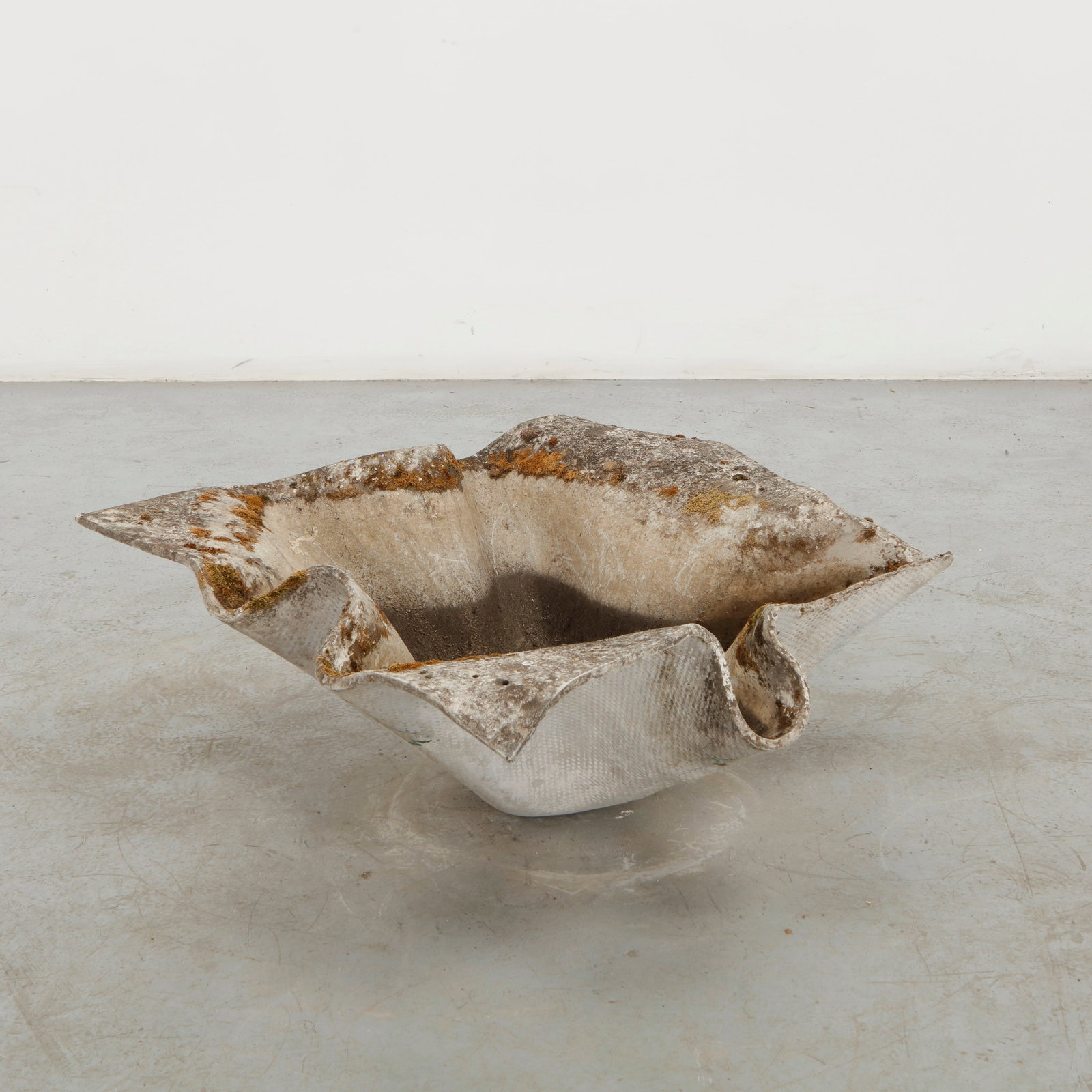 Willy Guhl, Large Elephant Ear Planter, 1960s: A large, shallow concrete planter distinguished by its broad, organic silhouette and gently undulating rim. Its low profile and monumental presence reflect Guhl celebrated transformation of