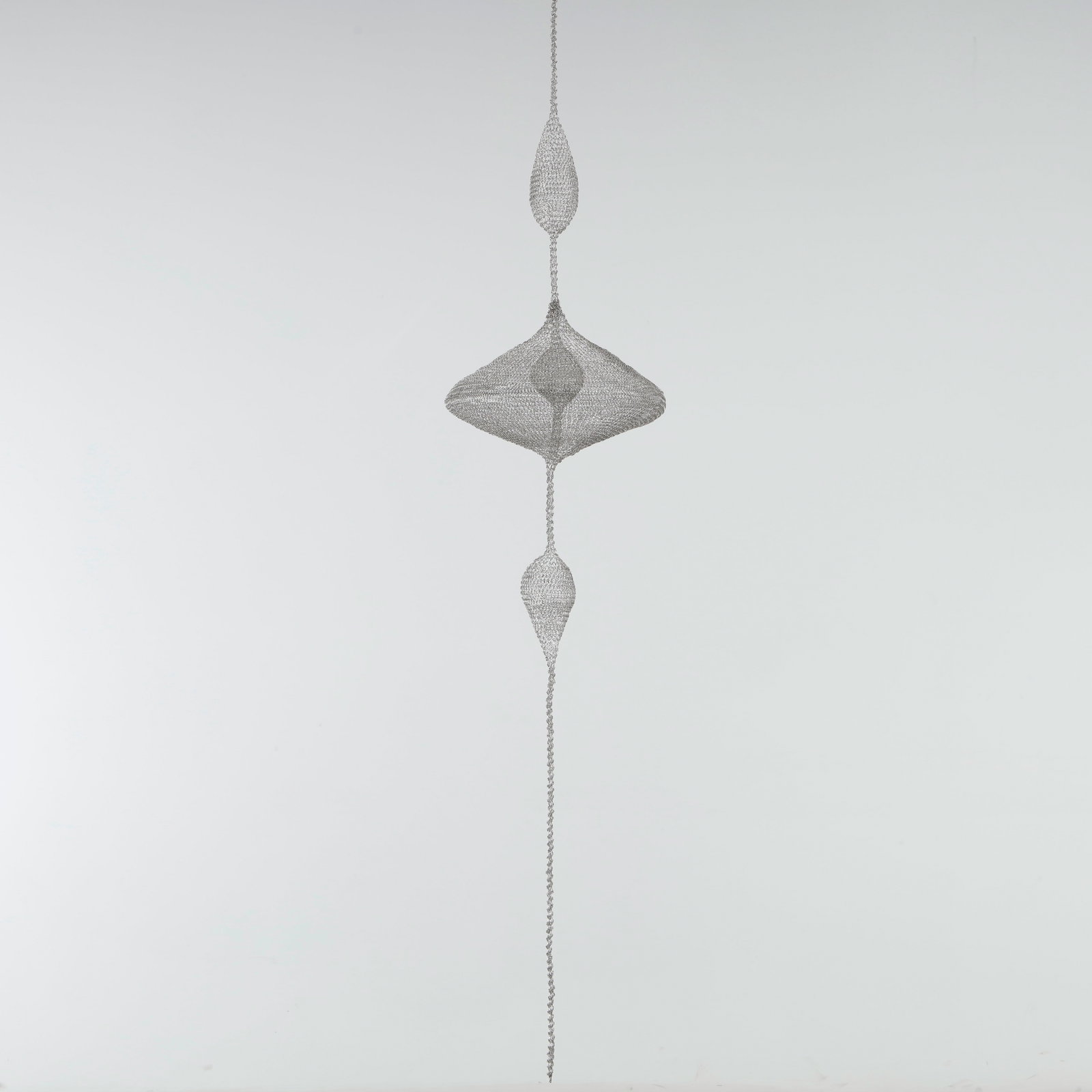 Noe Raya, Wire Sculpture: Hand-looped stainless steel wire sculpture, technique in the tradition of Ruth Asawa, executed entirely by hand. A vertical composition of three suspended forms, a slender teardrop, a broad