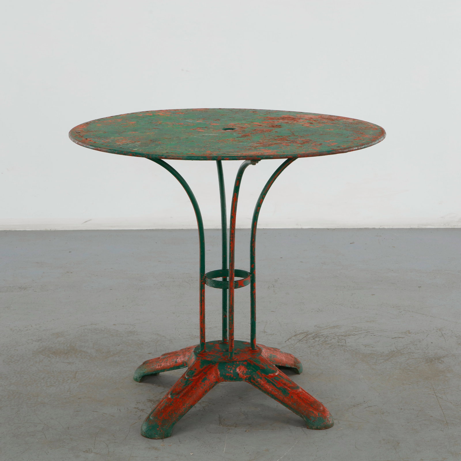 Parisian Round Garden Table, 1960s: Round outdoor table executed in painted metal, featuring a delicate pierced tabletop, scrolling apron and elegantly curved legs. The aged painted surface and ornamental wrought iron construction