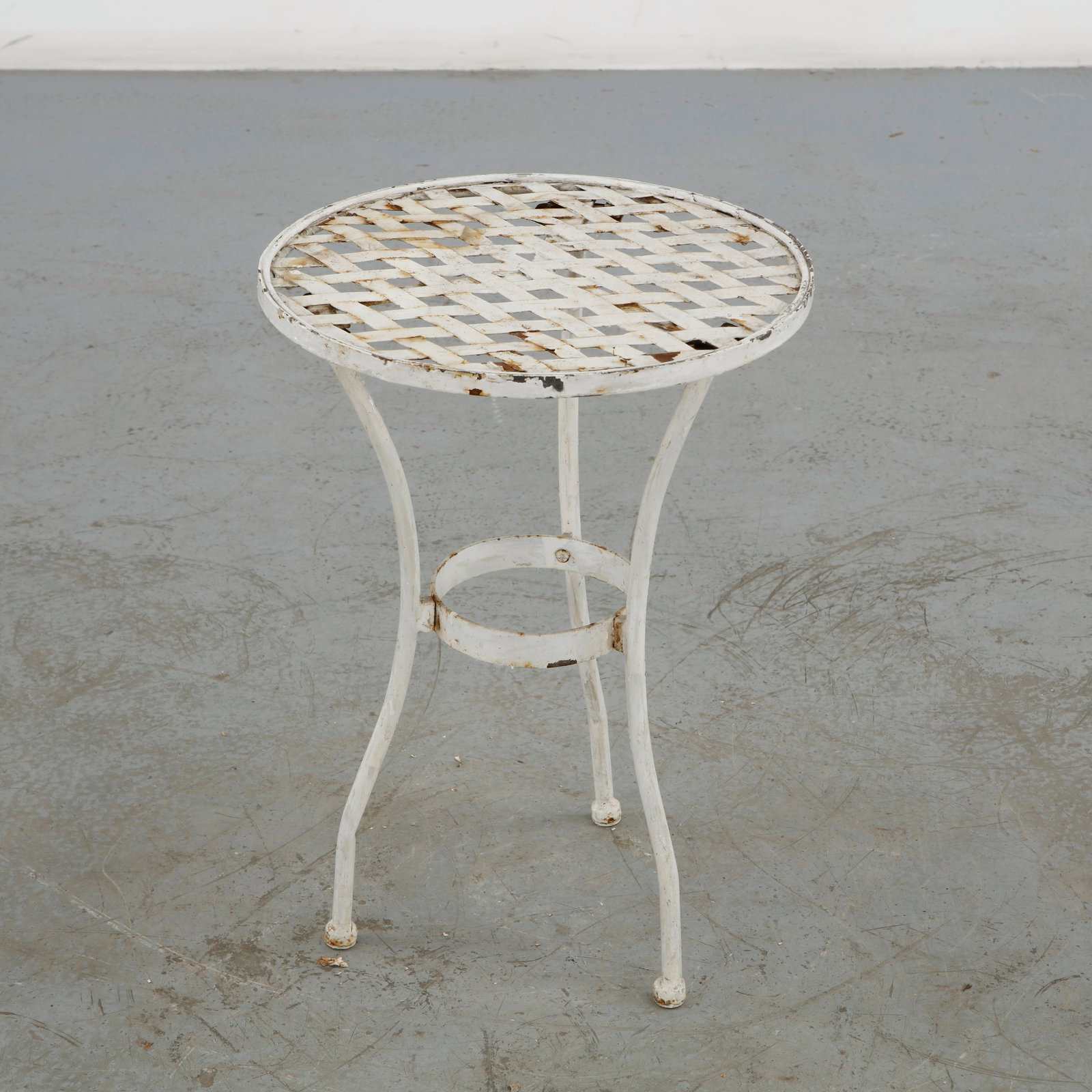 Small Wrought Iron Garden Table, 1960s: Small round garden table in wrought iron, featuring an openwork lattice top, elegantly curved legs and a circular stretcher. The worn painted surface and delicate construction embody the romantic