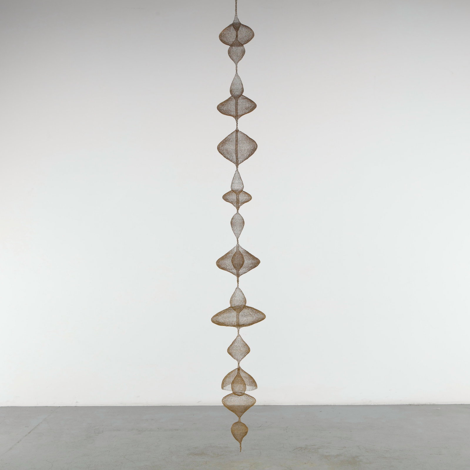 Noe Raya, Wire Brass Sculpture: Unnamed, translates spoken words into physical forms, bringing the virtues of Galatians 5:22, 23 into a long-hanging, fluid sculpture. Hand-crafted from thin brass wire using wire looping techniques