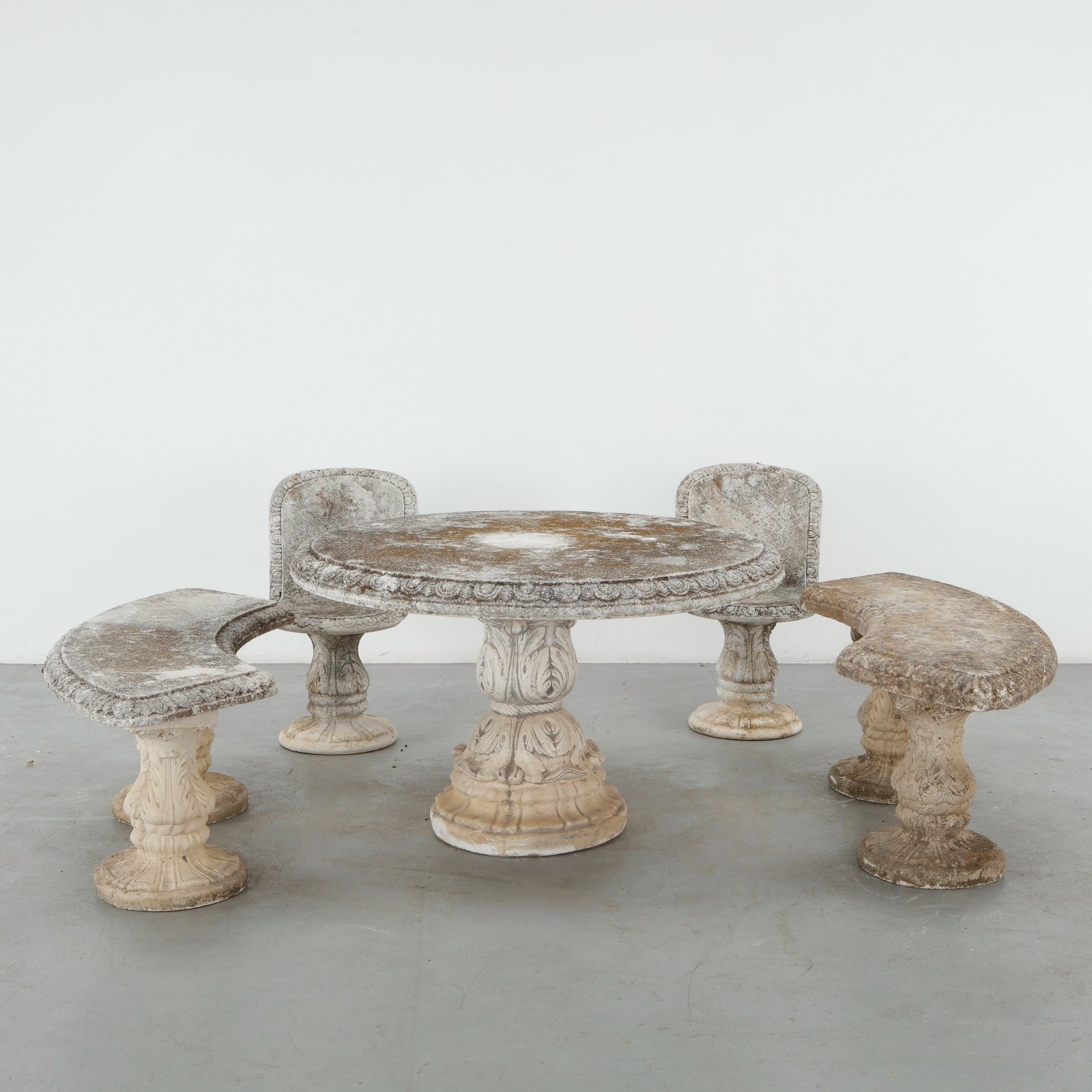 Ornate Stone Outdoor Dining Set, 1960s: A highly decorative outdoor dining ensemble in stone, comprising a round table, sculpted pedestal seating and two curved benches. Richly modeled architectural details and weathered surfaces give the s