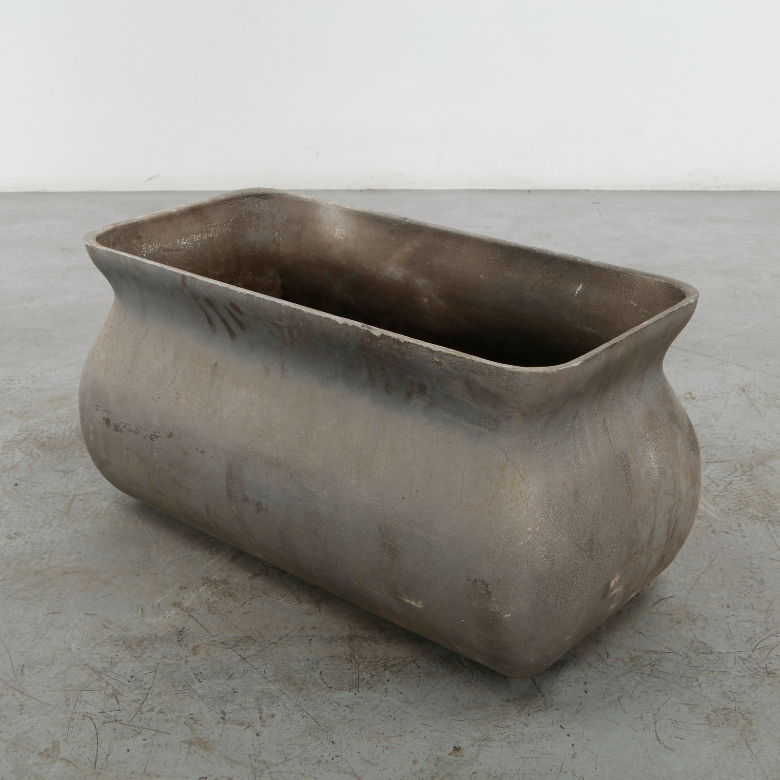 Willy Guhl, Sculptural Rectangular Planter, 1960s: A distinctive Willy Guhl planter in cast cement, distinguished by its elongated rectangular form and softly sculpted, cinched sides. The darkened surface and substantial construction emphasize Guhl ch