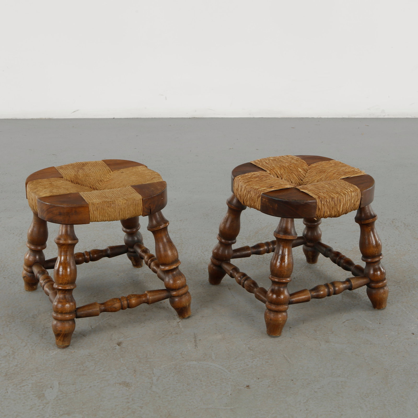 Pair of Rope Stools, 1960s: A distinctive pair of Rope stools, featuring richly turned solid-wood legs and stretchers supporting circular seats composed of segmented wooden elements bound with woven natural rope. The combination