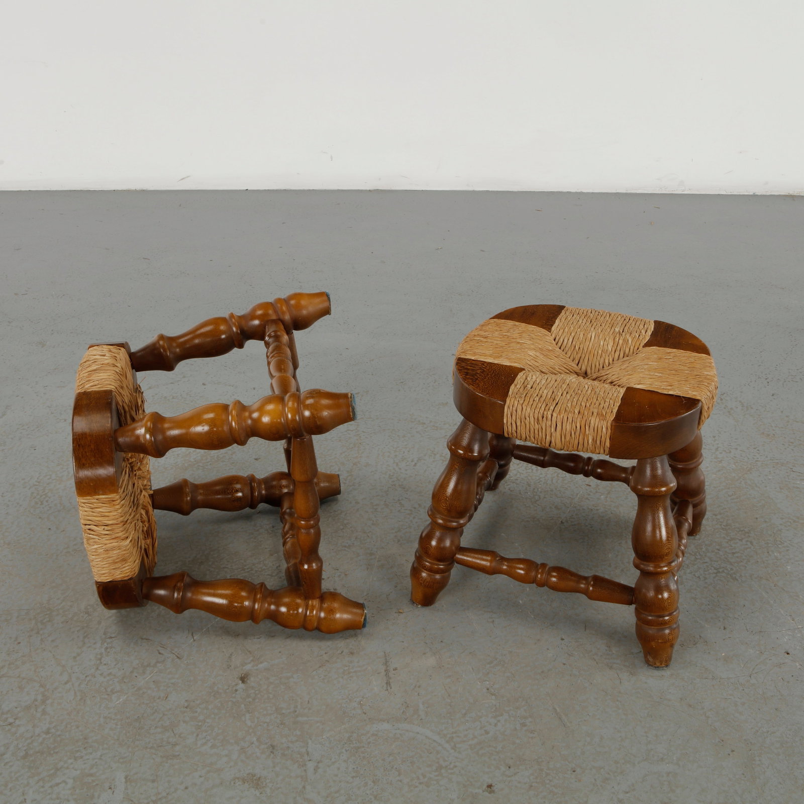 Pair of Rope Stools, 1960s: A distinctive pair of Rope stools, featuring richly turned solid-wood legs and stretchers supporting circular seats composed of segmented wooden elements bound with woven natural rope. The combination