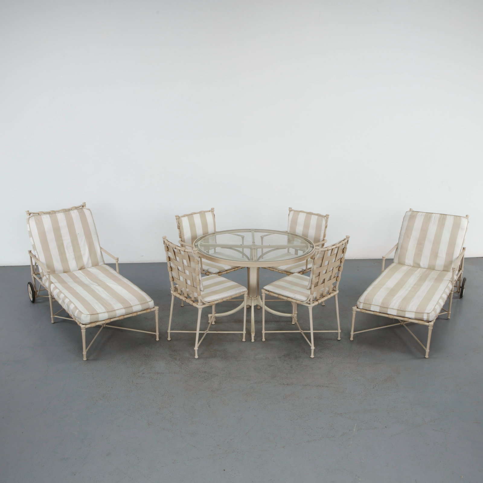 Brown Jordan, Florentine Wrought Iron Outdoor Dining Set with Matching Chaise Lounges, 1950s: An extensive Brown Jordan Florentine outdoor suite in painted wrought iron, comprising a round glass-top dining table on a four-legged pedestal base, four matching armchairs with woven strap seats and