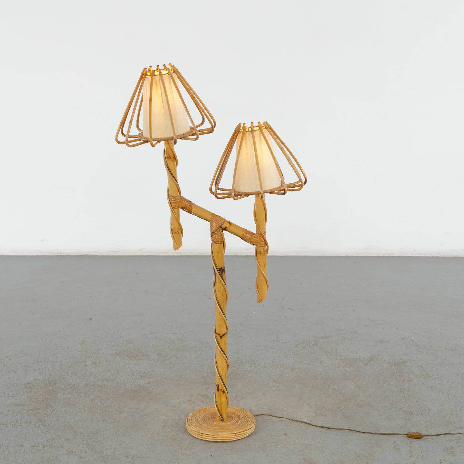 Louis Sognot, Double-Arm Rattan Floor Lamp, France, 1950s: This double-arm rattan floor lamp by Louis Sognot from the 1950s is a striking example of French midcentury organic design. Known for his innovative use of rattan, bamboo, and woven reeds during the