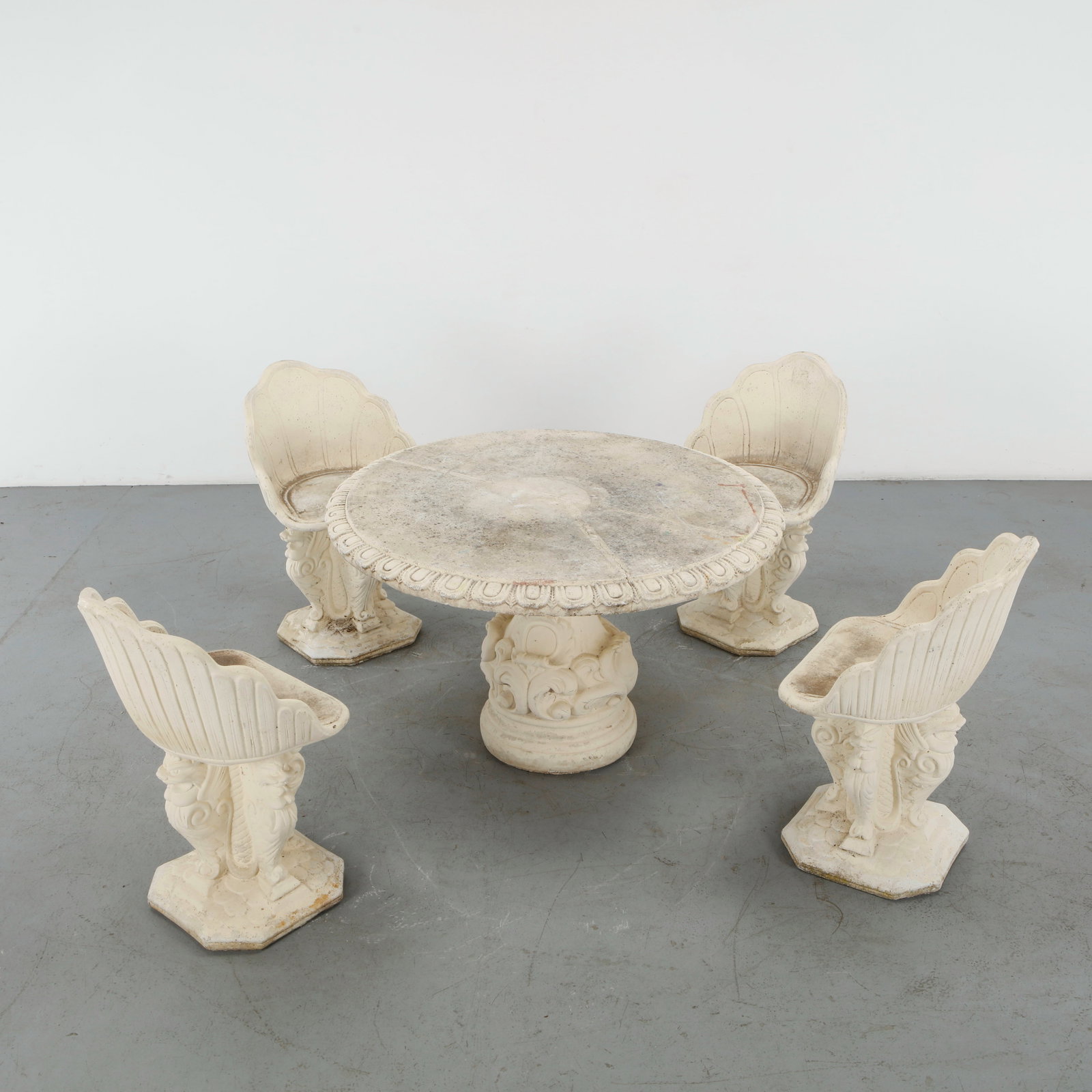 Stone Garden Dining Set, 1960s: An ornate Baroque-style outdoor dining set in a unique cream/off-white color. The set comprising a round table with richly adorned with classical Baroque relief carvings pedestal base and 4 chairs wit