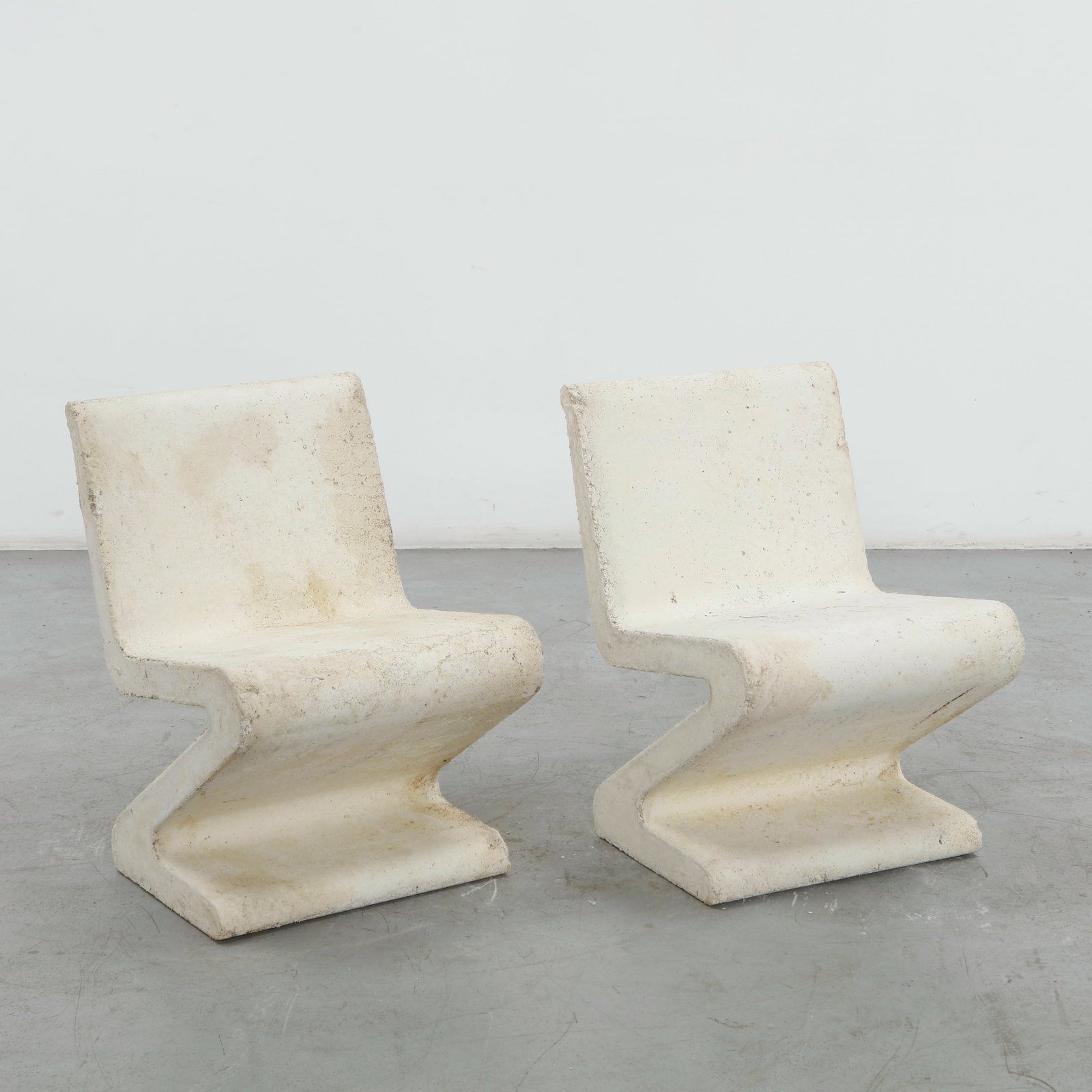 Pair of Zig Zag Concrete Chairs, 1960s: Executed in molded concrete, these sculptural chairs reinterpret the iconic zig-zag silhouette with monumental weight and geometric precision. Striking outdoor forms with enduring presence. Chair: Hei