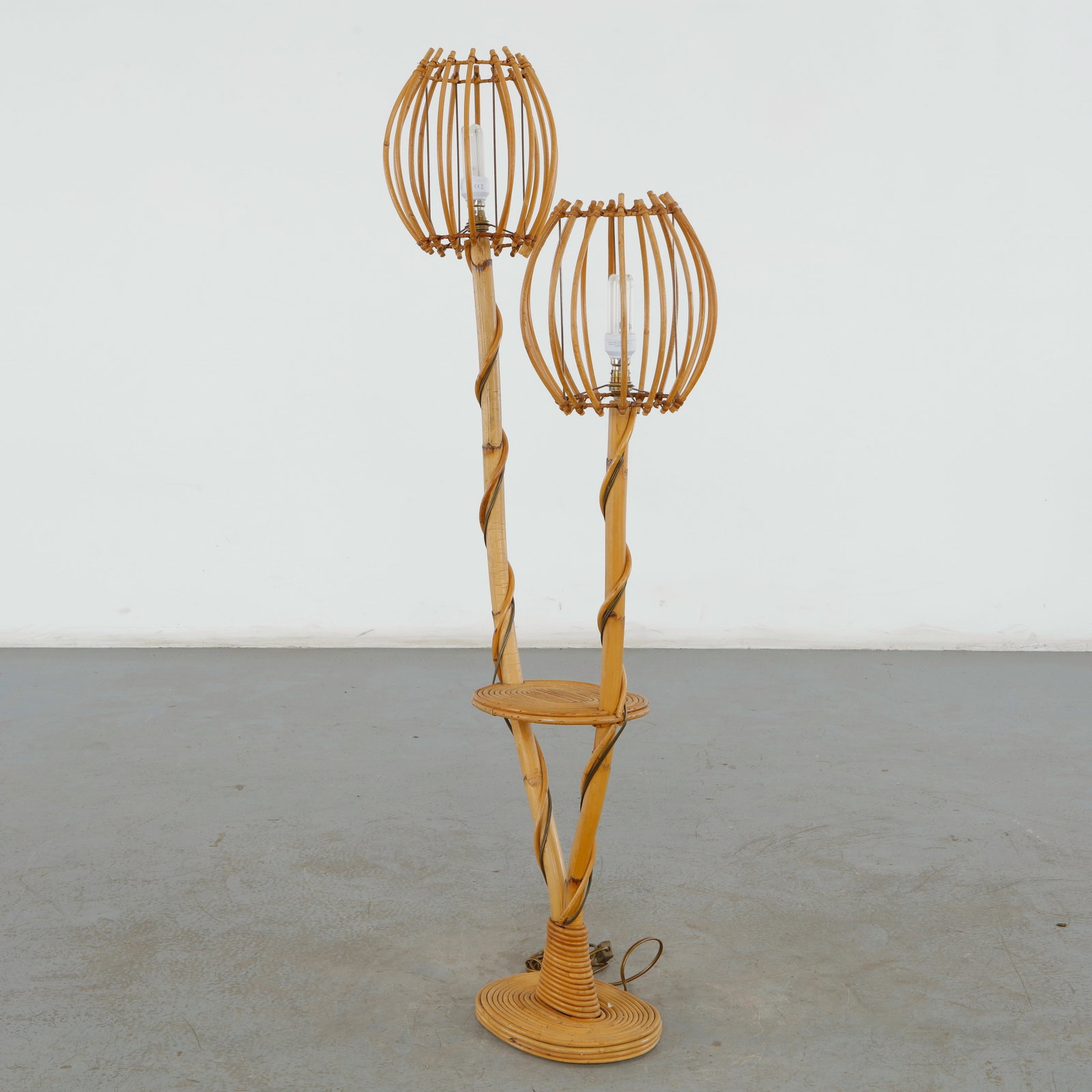 Louis Sognot, Double-Light Rattan Floor Lamp, France, 1950s: This vintage double-light rattan floor lamp is a striking example of 1950s French midcentury organic modernism, designed in the distinctive botanical style popularized by Louis Sognot. It translates n