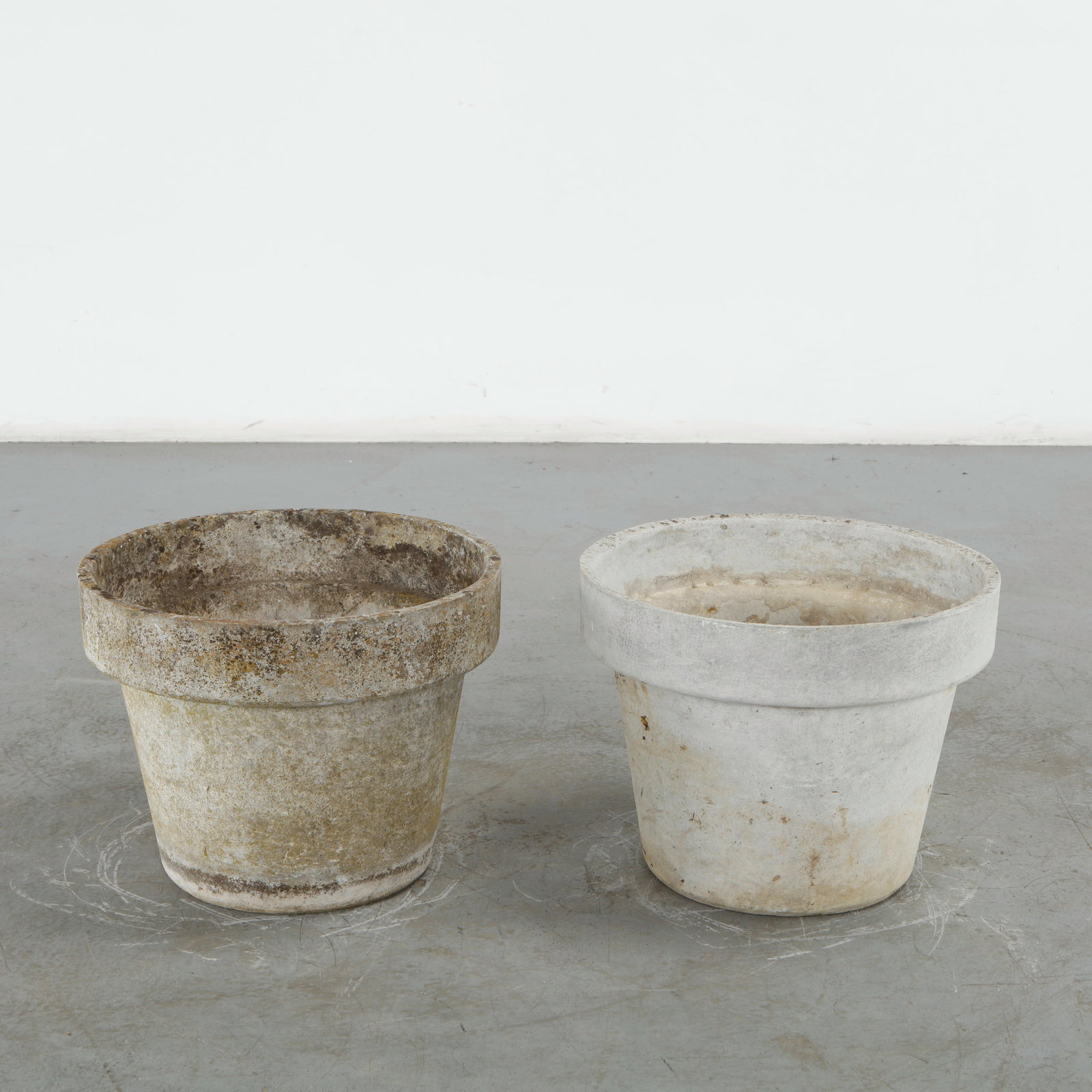 Willy Guhl, Pair of Round Planters, 1960s: Pair of substantial round planters in concrete, featuring softly tapering bodies and pronounced upper rims. Their restrained geometry is complemented by an authentic weathered surface developed
