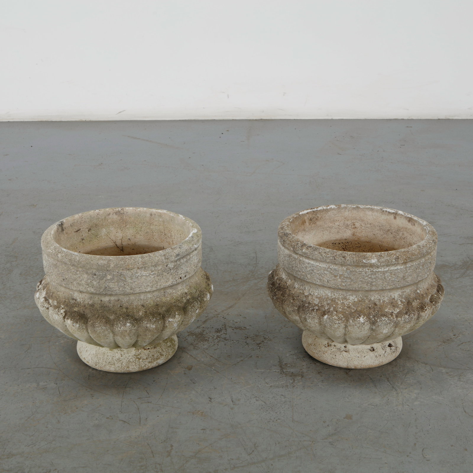 Pair of Fluted Cast Stone Planters, 1960s: This pair of fluted cast stone planters from the 1960s features a robust, classical silhouette adapted for mid-century European garden landscapes. Their deep, structured forms perfectly blend