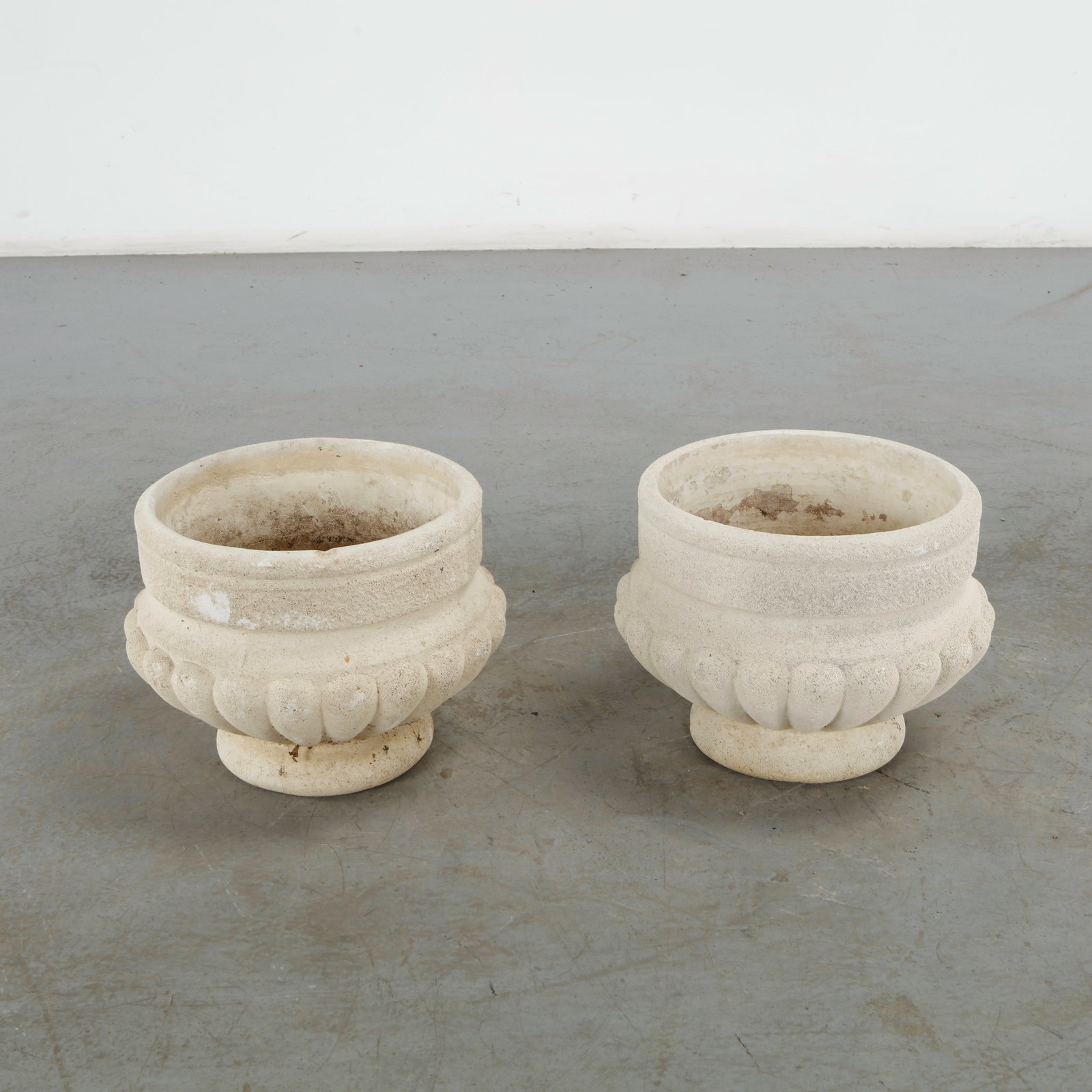 Pair of Fluted Cast Stone Planters, 1960s: This pair of Grandon Fr?res "Coppa" cast stone planters, dating to circa 1960s, exemplifies mid-century French garden architecture. Blending classical Roman geometry with a heavy, textured f