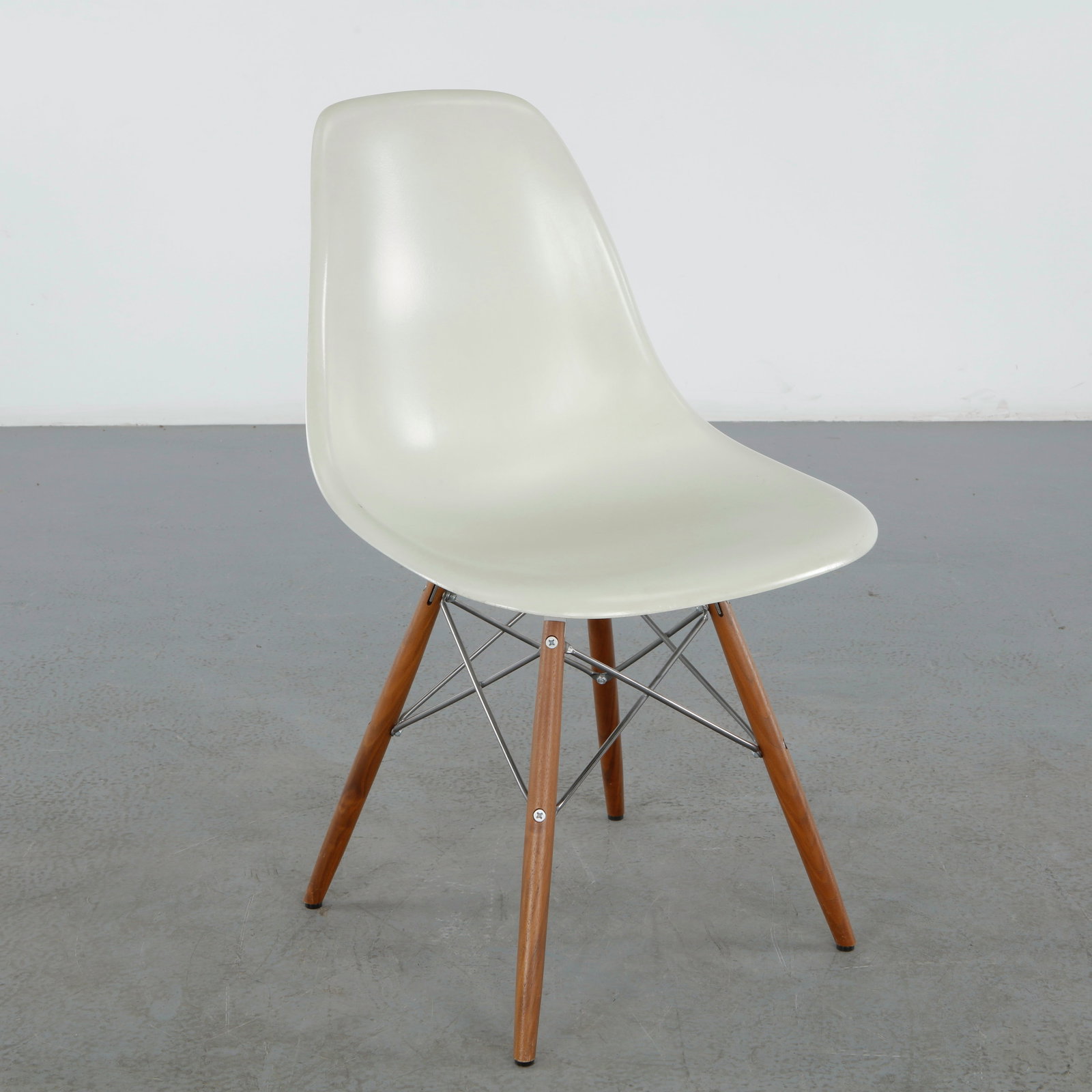 Charles and Ray Eames for Herman Miller, Molded Plastic Side Chair: An Eames molded fiberglass side chair for Herman Miller, its shell in warm white on a walnut dowel-leg base with chromed steel cross-bracing. Height: 32 in. Width: 18.5 in. Depth : 20.5 in. Seat