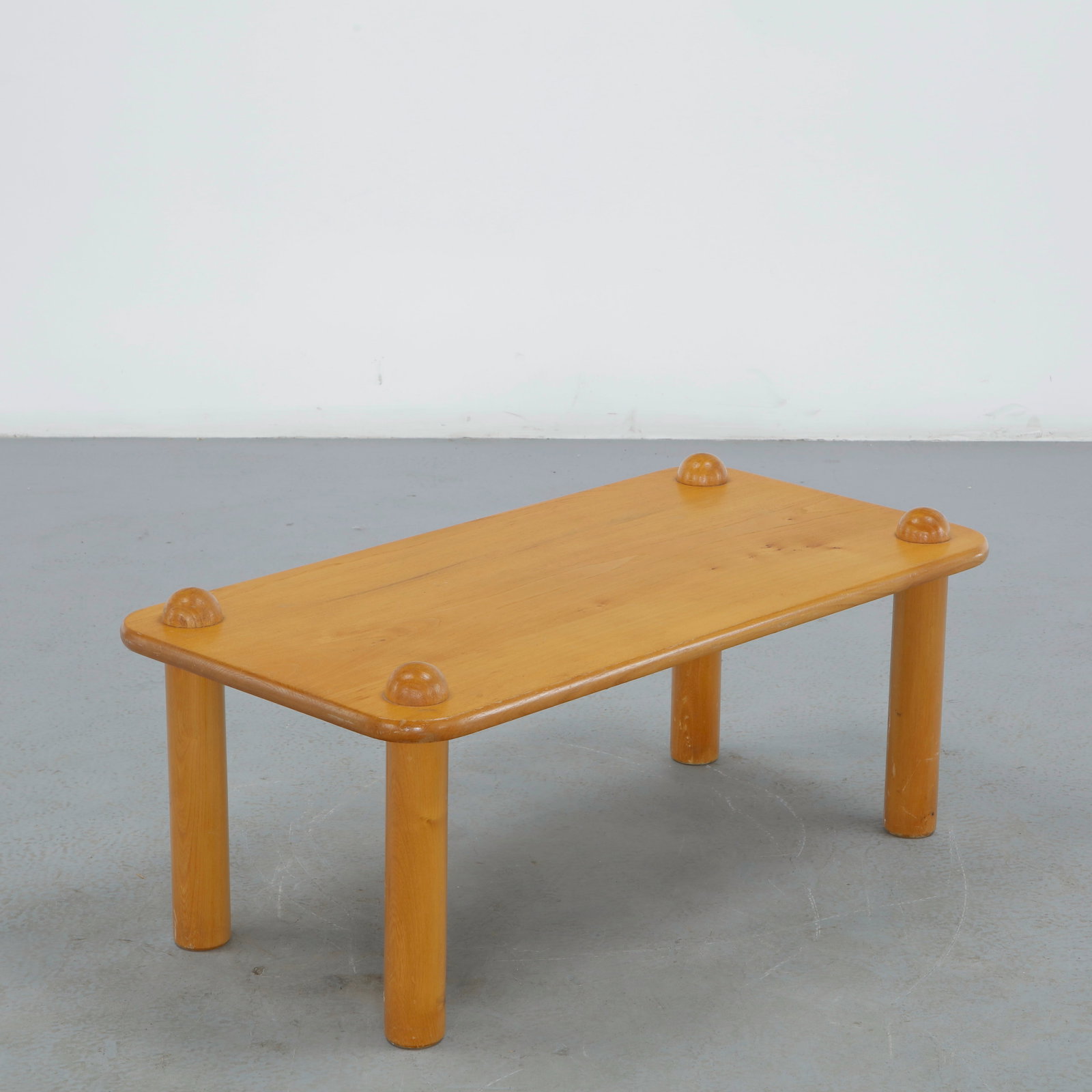 Solid Wood Coffee Table in the style of Charlotte Perriand, 1970s: A rectangular pine coffee table in the style of Charlotte Perriand, its thick cylindrical legs rising through the top and capped with rounded dome finials at each corner. Height: 13.75 in. Length: