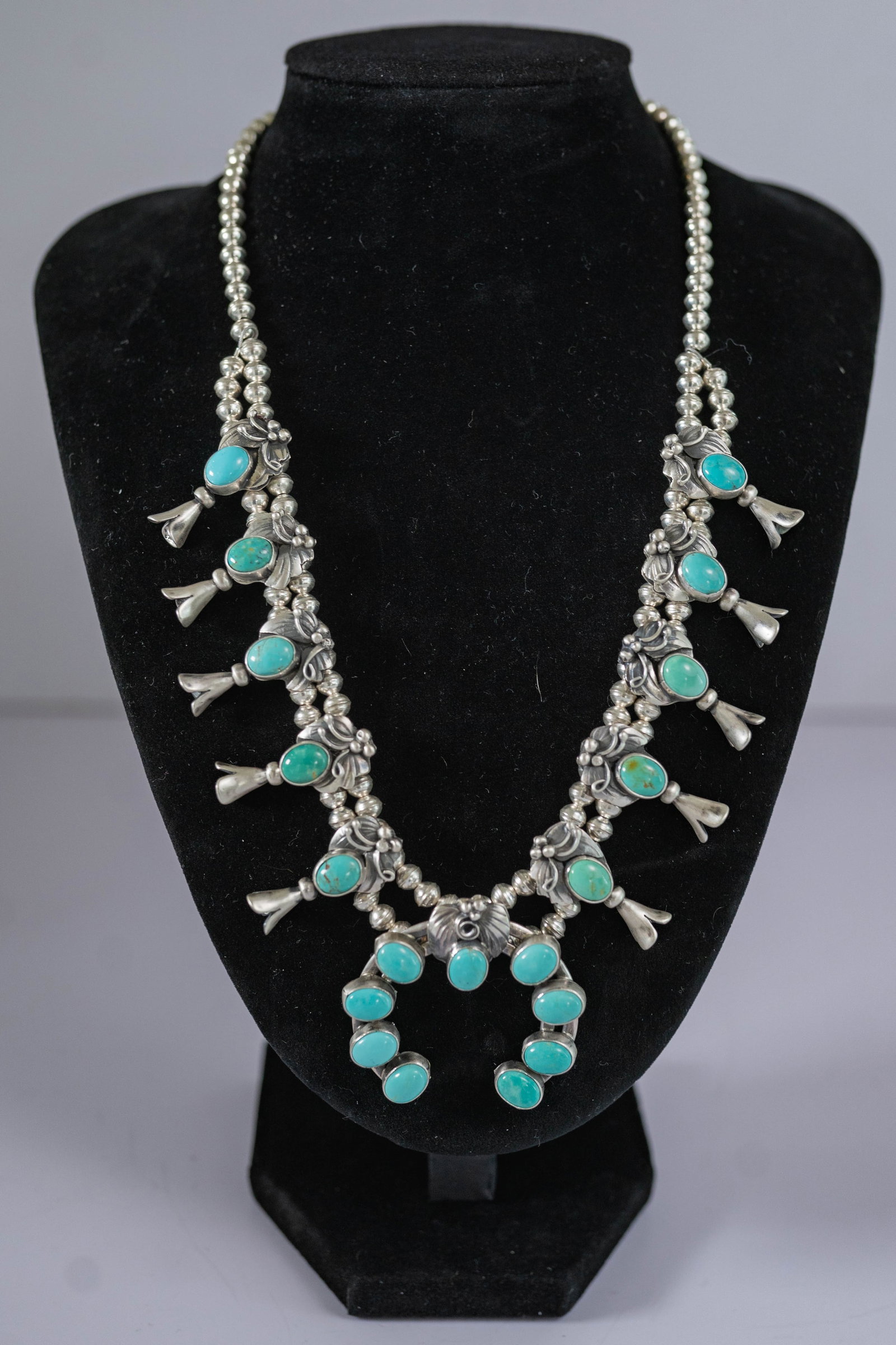 Lydia Begay Tyrone Turquoise Squash Blossom: Native American Navajo Master silversmith Lydia Begay fantastic sterling silver squash blossom necklace featuring AAAAA Rare Tyrone turquoise gemstones with leaf, berry and vine appliques. Necklace fe