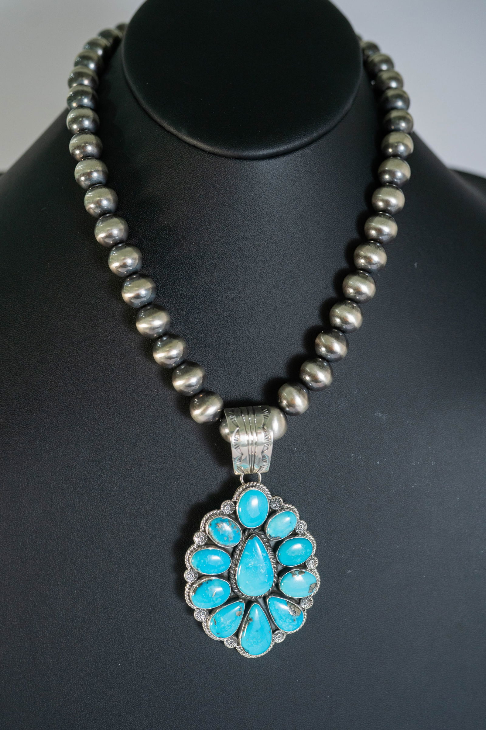 Radiant Ella Linkin Pendant Necklace: Native American Navajo Master Silversmith Ella Linkin sterling silver pendant featuring radiant AAAAA Kingman Turquoise gemstones. It is surrounded by scalloped twisted wire with rosette spacers and a