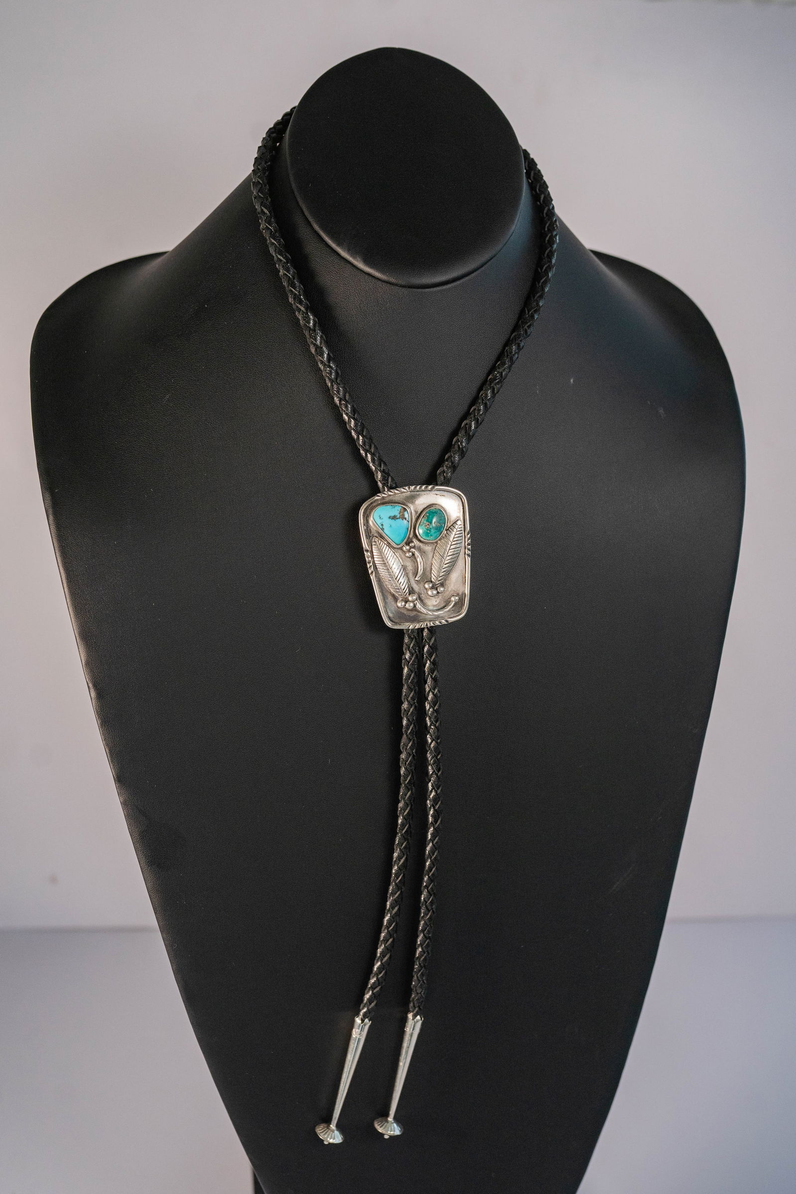 Vintage Sterling Silver & Turquoise Bolo Tie: Native American Navajo vintage Sterling Silver bolo tie with (1) AAAA blue Kingman Turquoise gemstone and (1) AAA green Kingman turquoise gemstone hand tool, carved and etched with leaf berry and vine