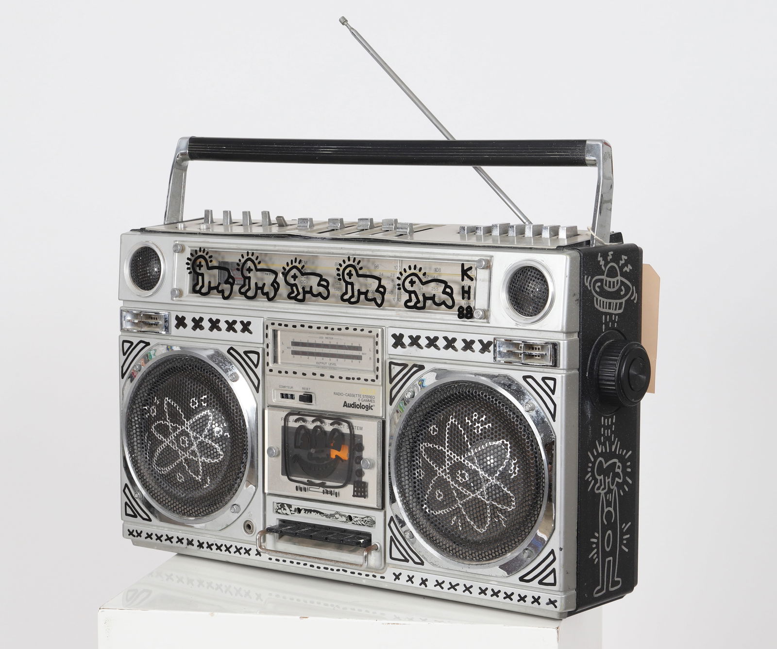 Keith Haring (1958-1990) d'après "Boom Box" Poste radio cassette stereo portable AUDIOLOGIC: Keith Haring (1958-1990) d'après "Boom Box" Poste radio cassette stereo portable AUDIOLOGIC portant des dessins au marqueur d'après Keith Haring. Dimensions: H:32; L: 54; P: 13,5cm