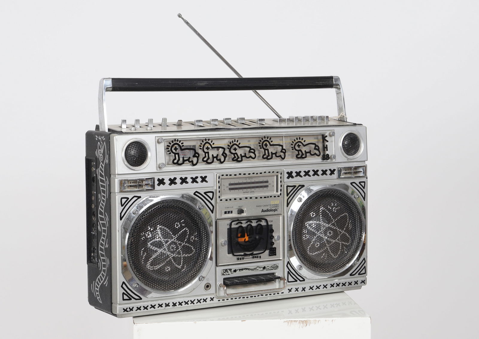 Keith Haring (1958-1990) d'apres: Keith Haring (1958-1990) d'apres "Boom Box" Poste radio cassette stereo portable AUDIOLOGIC portant des dessins au marqueur d'apres Keith Haring. Dimensions: H:32; L: 54; P: 13,5cm - Weight: 0 - Shipp