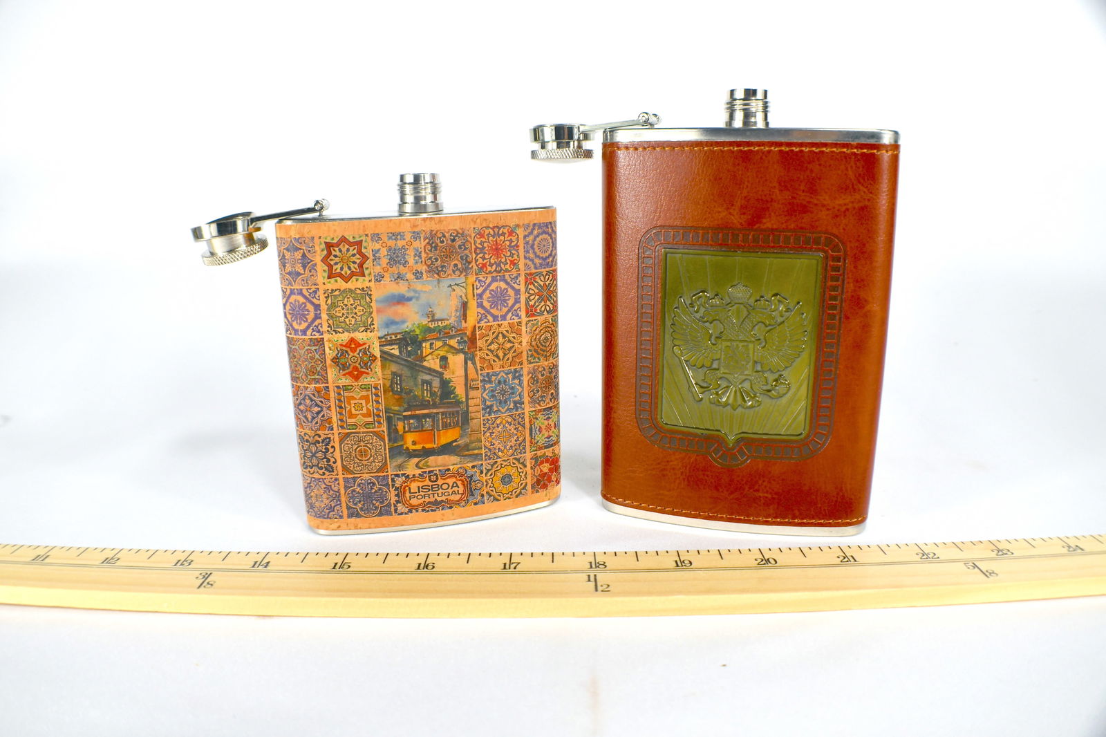 2 Stainless Steel Flasks: One wrapped in paper One wrapped in leather with a crest 1 is 7-ounces and the other is 9-ounces