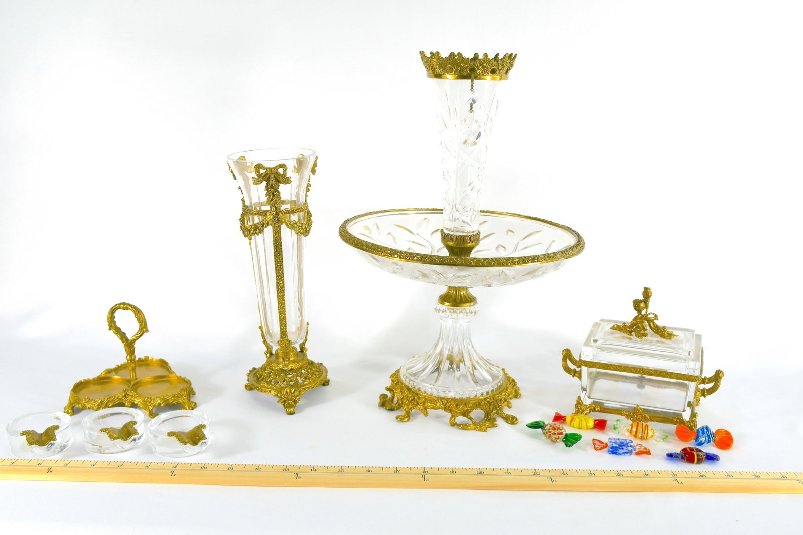 Four Pieces Of Bronze And Cut Crystal Accessories: Cigar holder for 3 cigars 5"tall Candy Dish with 6 pieces of glass candies- 4 1/2" long x 4" wide Vase 10 1/4" tall No markings Cut Crystal flower vase with round tray in the middle with gilt bronze a