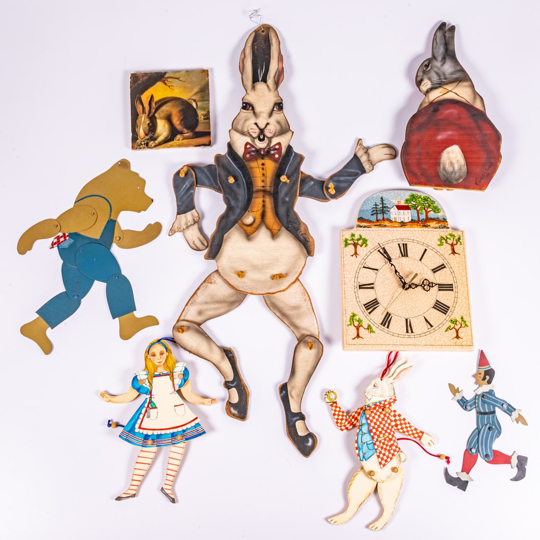 A Group of Rabbit Themed Articulated Wooden Toys: A Group of Wooden Articulated Rabbits, Bear, Clock and Elf, Together with Alice in Wonderland and White Rabbit characters. Also including a ceramic clock face. Clock dimensions: H: 12 x W: 9 1/2 in.