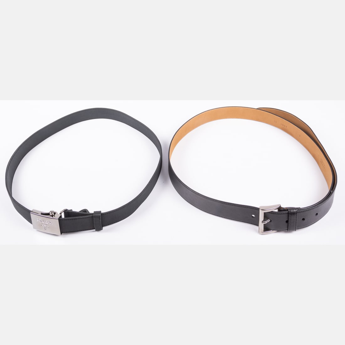 Two Belts By Prada: Two Belts By Prada, One belt is fashioned from leather with a gunmetal colored buckle. Interior marked Prada Made in Italy 36/90. Measures 1 1/4 inches wide, 50 3/4 inches total length. Can be belted