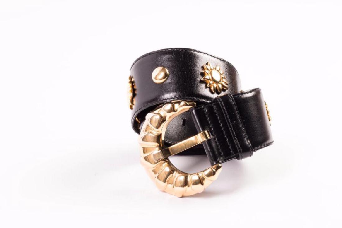 ESCADA: Large ceinture en cuir noir, boucle en métal doré. Décor de soleil et petits ronds en metal doré. Taille indiquée : 38. Largeur : 5 cm. Longueur totale du cuir : 83 cm. Bon état.