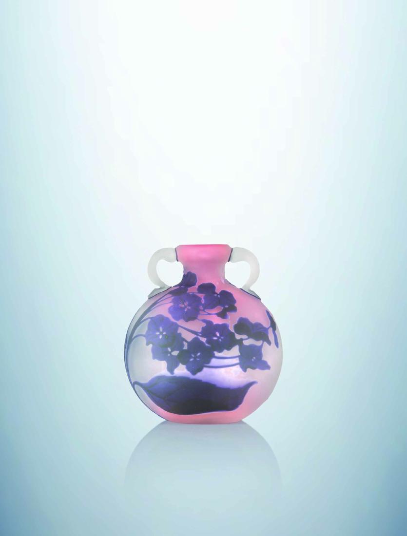 ETABLISSEMENTS GALLE Vase meplat de forme gourde a: eTABLISSEMENTS GALLeVase meplat de forme gourde a anses appliquees a chaud. epreuve en verre multicouche degage a l'acide a decor d'hortensias violine et vert sur fond opalescent nuage de rose. Signat