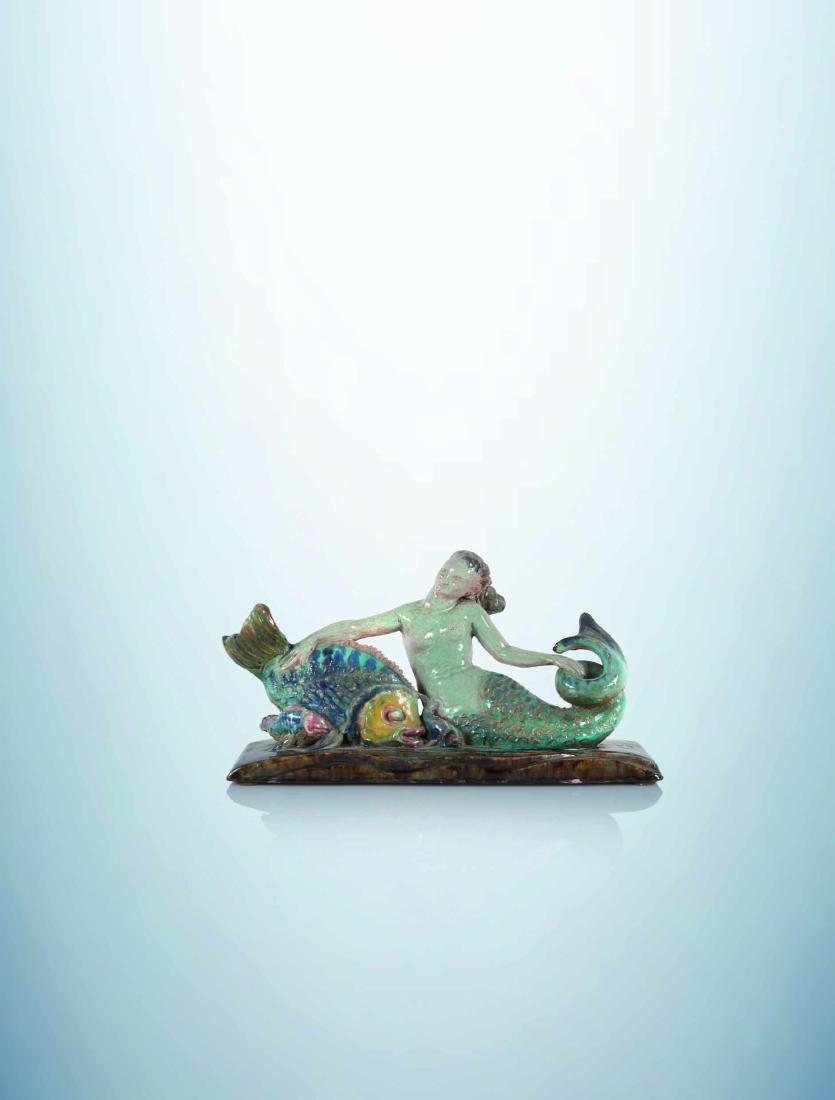 RENE BUTHAUD (ATTRIBUE A) Sirene et ses poissons.: RENe BUTHAUD (ATTRIBUe a)Sirene et ses poissons.Sculpture en ceramique emaillee bleue, rose et verte sur terrasse a petites vagues (bras restaure).Haut. 25 cm Long. 39 cm Prof. 12 cmEnameled ceramic s