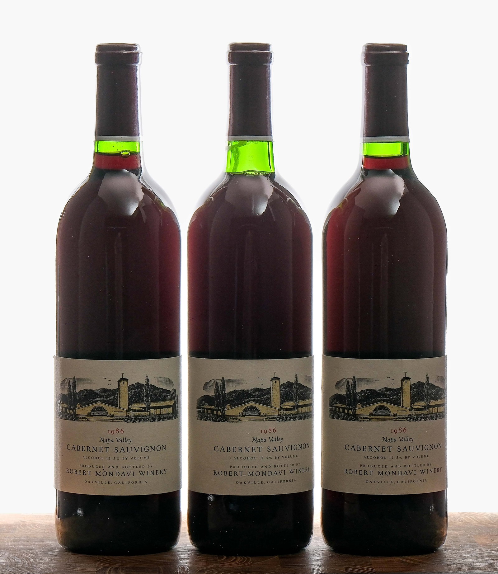 Robert Mondavi Cabernet Sauvignon 1986 Group (3): Group of 3 bottles with a 1986 vintage. Fill levels are mid-neck, base neck and top shoulder respectively (some seepage evident on this last bottle). 12.5% ALC/VOL. Foils appear excellent. Labels very