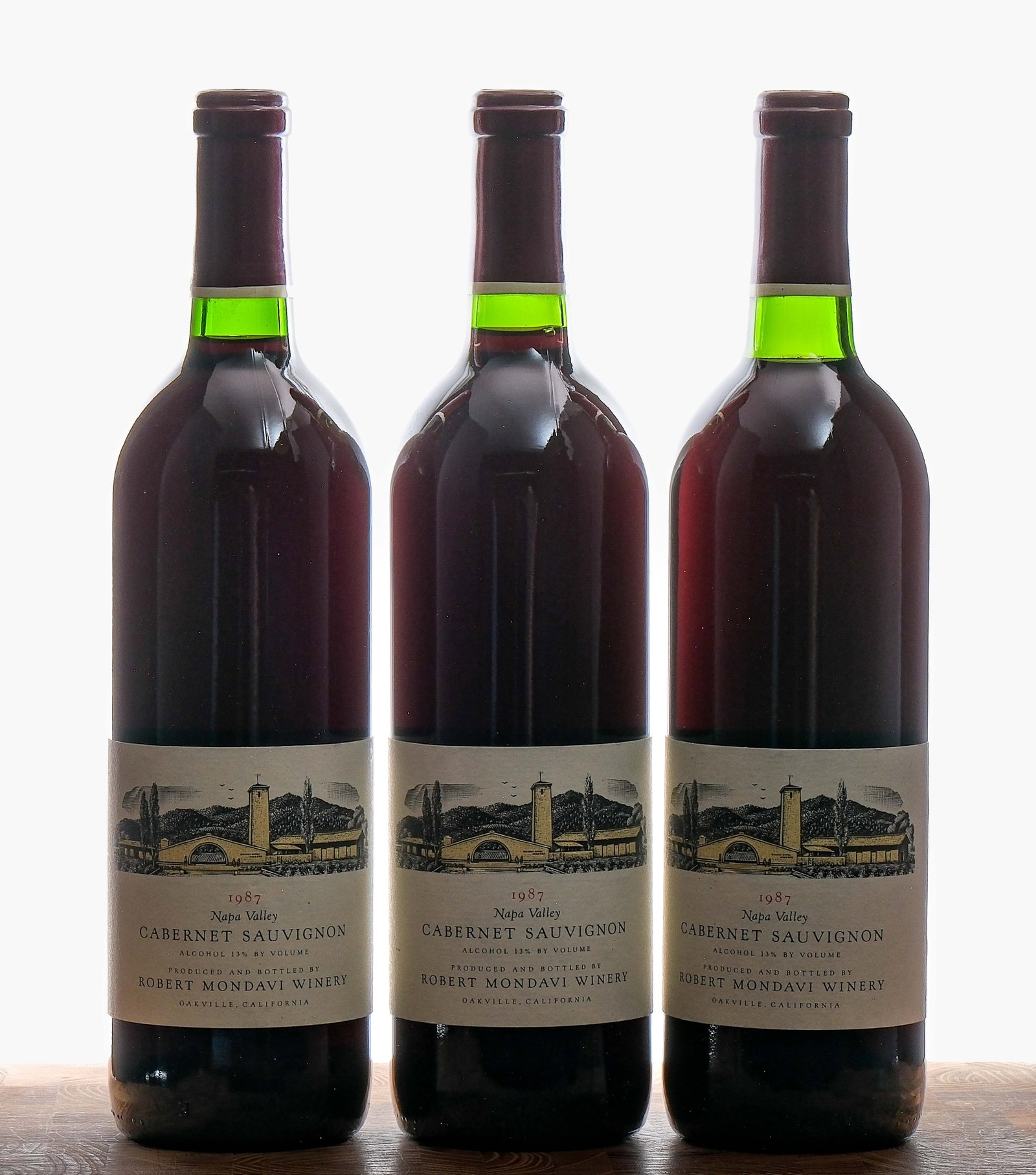 Robert Mondavi Cabernet Sauvignon 1987 Group (3): Group of 3 bottles with a 1987 vintage. Fill level on two of the bottles is base neck, the third at mid neck. Some sediment on necks. 13% ALC/VOL. Foils excellent. Labels very good (some nicks present