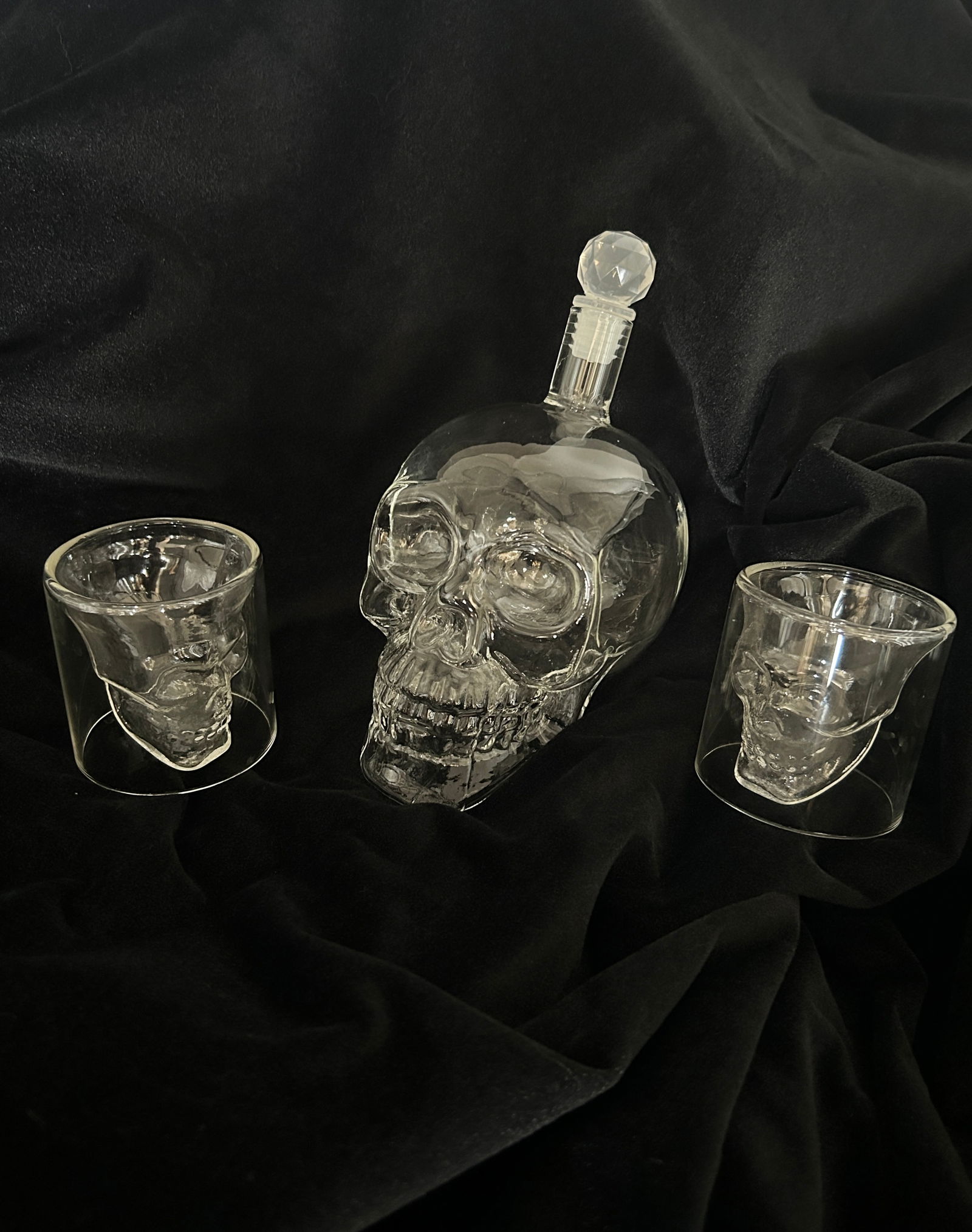 (3) Glass Skull DECANTER and Glasses: 3 part set including a glass scull with stopper and two glasses DIMENSIONS: 6 H X 6 W X 4 DEPTH in INCHES each glass is 2.5 x 2.5 The live auction begins at 11 AM EST Sunday, March 17th. Full c
