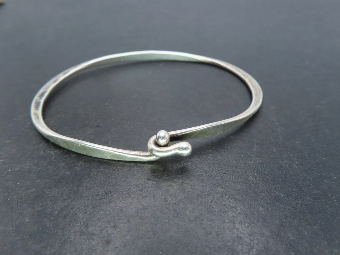 James Avery Hammered Sterling Silver Bangle Bracelet, 8.2g: James Avery sterling silver bangle bracelet. Eye and hook style with hammered surface. Signed AVERY, and marked as STERLINGLight wear and toned to luster, great condition. Inner circumference is about