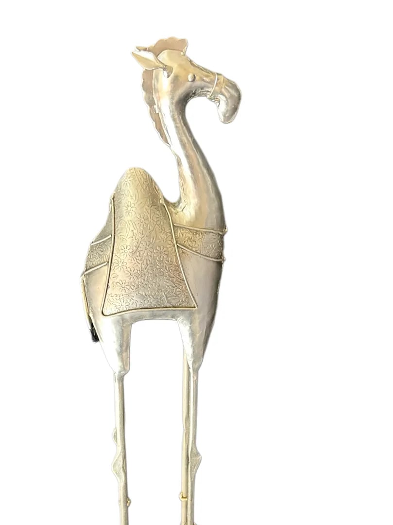 Silver Tone Metal Camel Sculpture 27in Tall: Silver Tone Metal Camel Sculpture 27in TallMounted on a square metal base for stability, this camel makes a wonderful statement piece for entryways, living rooms, offices, or covered outdoor spaces. P