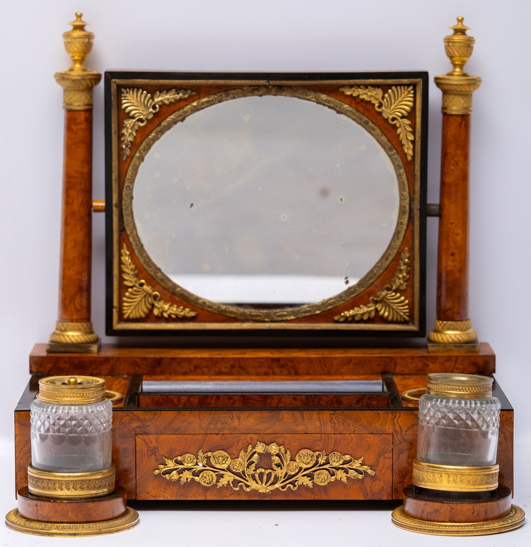 Ormolu Mounted Burr Wood Inkstand 19th century: 19th century, possibly First Empire, unmarked, in the form of a vanity, mixed wood secondary, two columns with engine turned urn capitals and bases framing an oval swivel mirror with palmette and laur