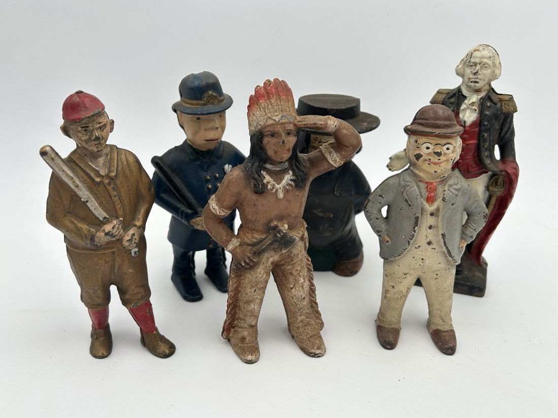 Grouping of 6 Figural Cast Iron Still Banks- includes TY COBB and George Washington: This lot includes 6 antique to vintage figural cast iron examples. From left to right- circa 1920 Ty Cobb by A.C. Williams, British Bobby with nightclub, Native American Squaw with axe, Amish man, cir