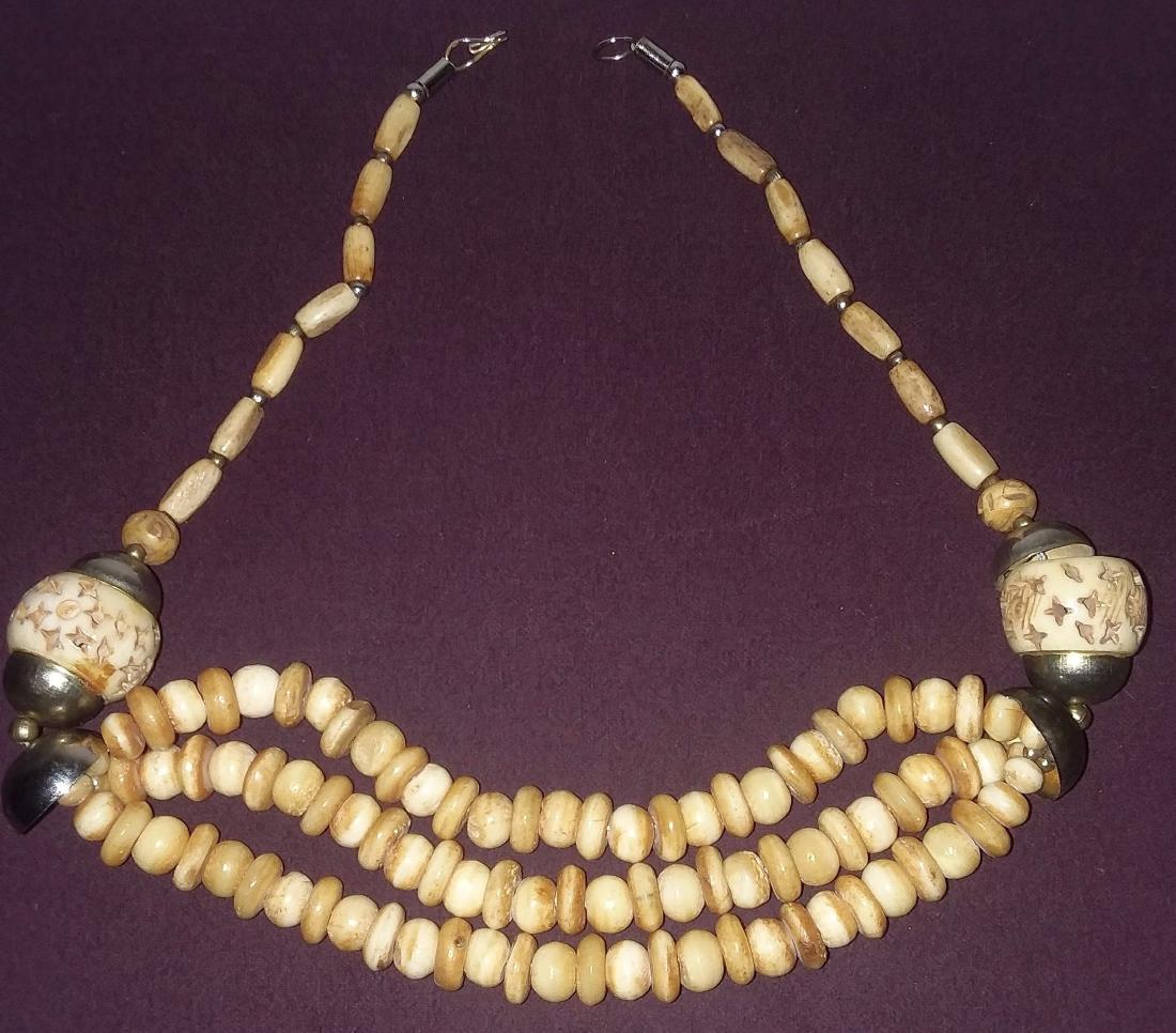 TRIBAL SILVER W/ ANTIQUE HAND CARVED & PIERCED BONE: A Tribal silver w/ antique hand carved & pierced bone in fine condition. 21" long.