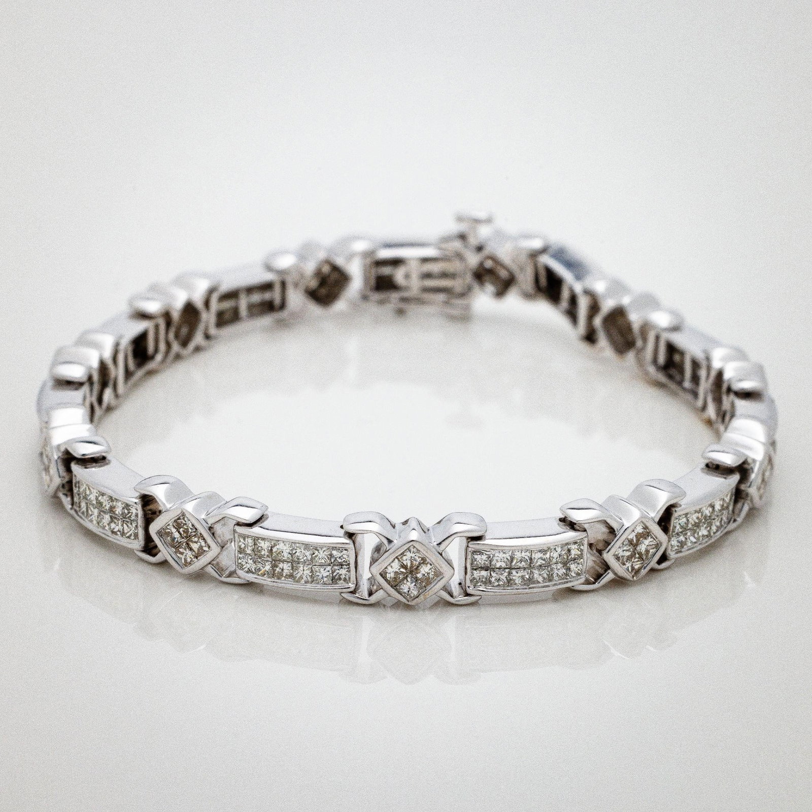 14kt White Gold Invisible Diamond Tennis Bracelet: An extremely fine tennis bracelet featuring 22 stations of invisible set princess cut diamonds. The bracelet width is 6.5mm. This bracelet is very substantial yet elegant and simple. The pictures cann