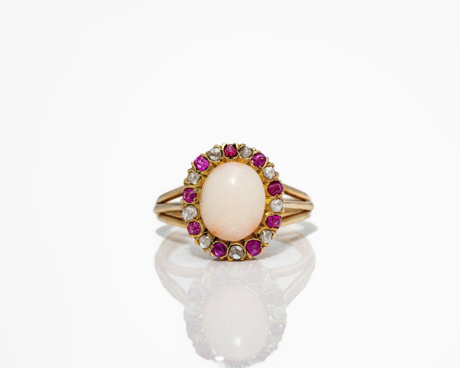Antique 18kt Gold Coral Burmese Ruby Diamond Ring: A refined true antique ballerina-style ring centered by a vibrant natural coral cabochon; displaying rich; warm coloration and smooth surface character. The coral serves as a bold and elegant focal po
