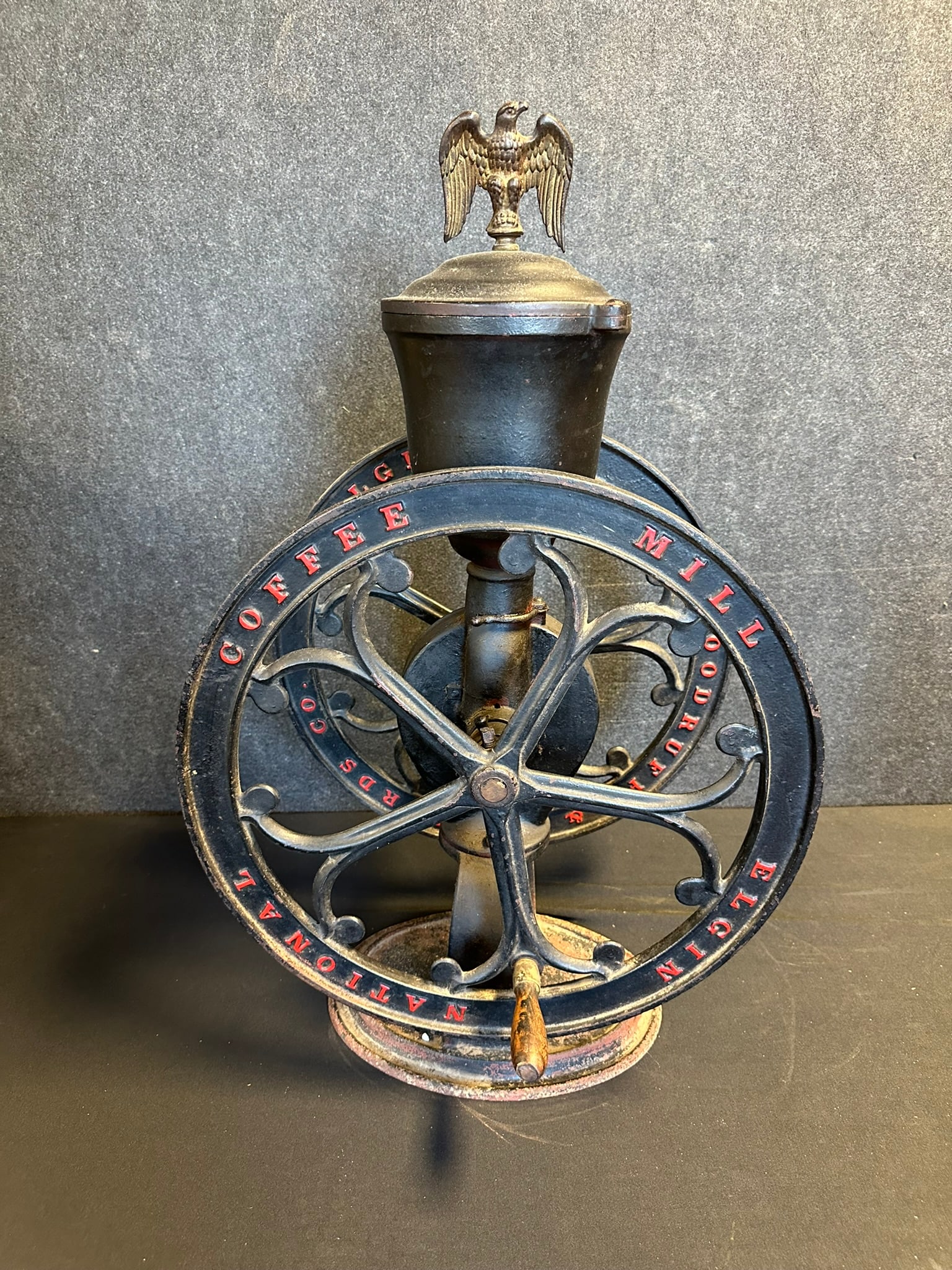 Antique Elgin National Coffee Mill w/ Original Black & Red Paint & Eagle Topper: Wheel measures 19" diameter x 32" tall x 12" wide - great original mill with great surface. One handle in the hopper as shown.