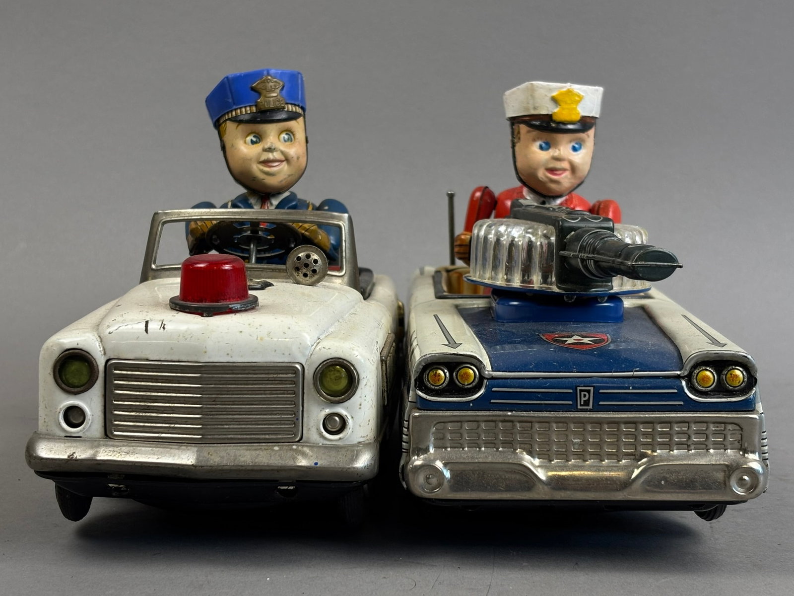 2 Nomura Japan Tin Battery OP Police Patrol Toys: This lot features a pairing of Nomura Japanese tin battery operated Police Patrol cars. The Gunner Patrol Car powers on, moves, and shoots, the other police car toy is inop and may not be complete. Th